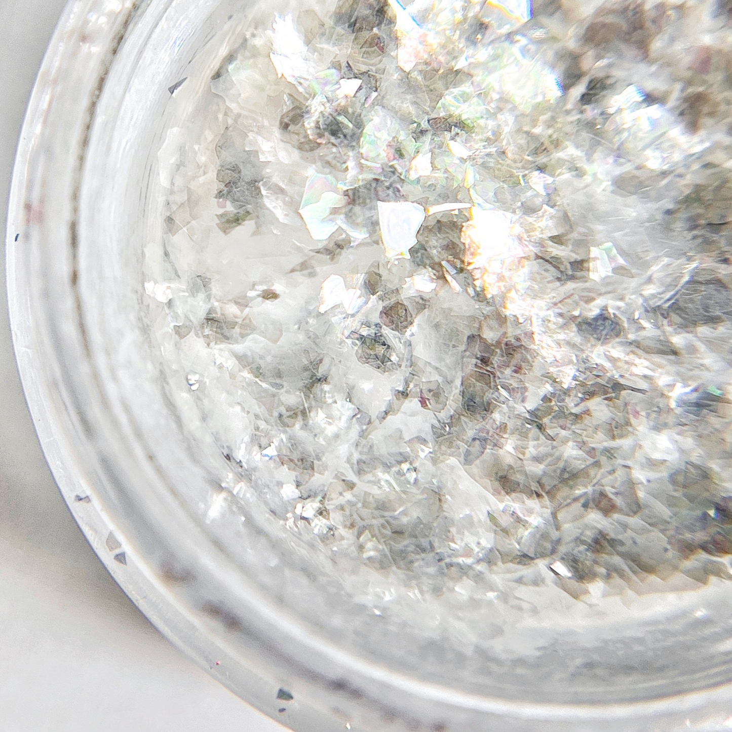 Sheer white flakes in clear jar on white background.
