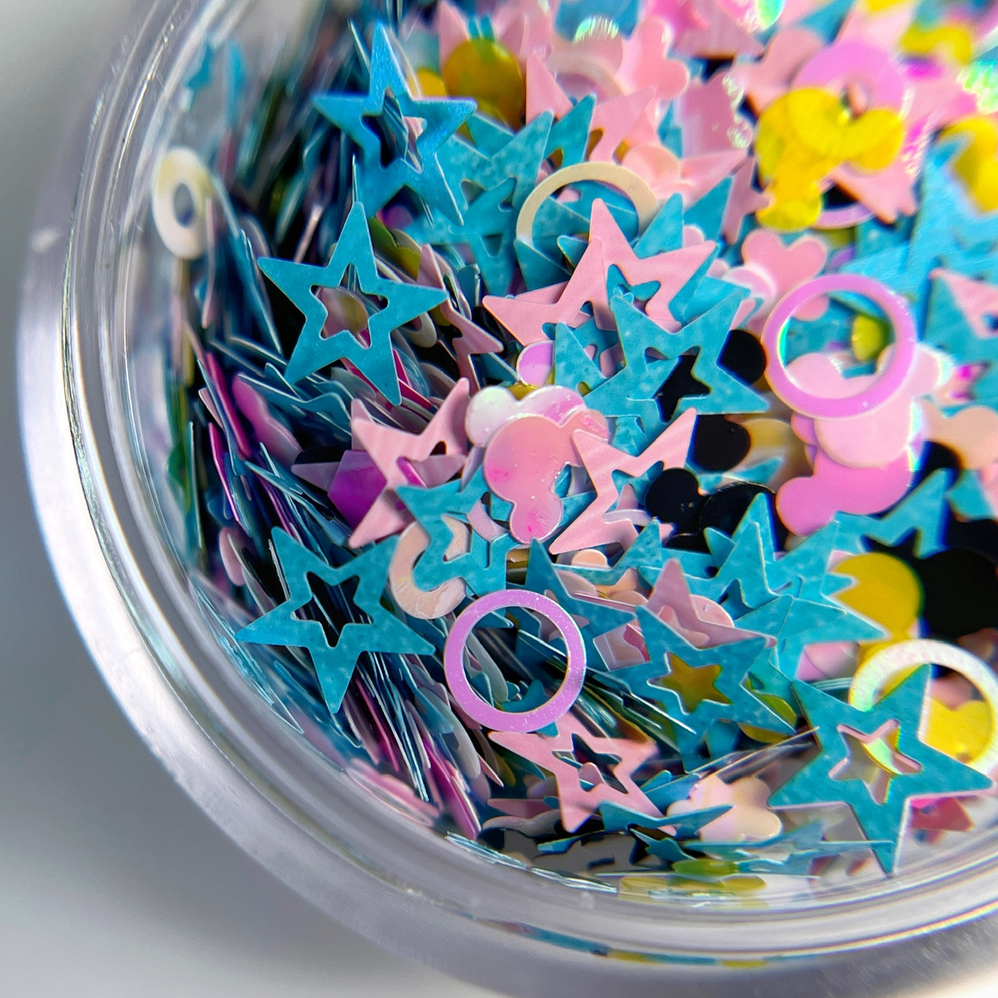 Multicolor glitter mix in clear jar on white background.