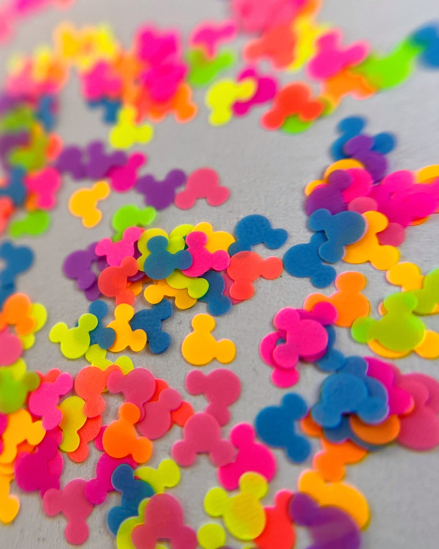 Multi-colored mouse shaped glitter scattered on white background.
