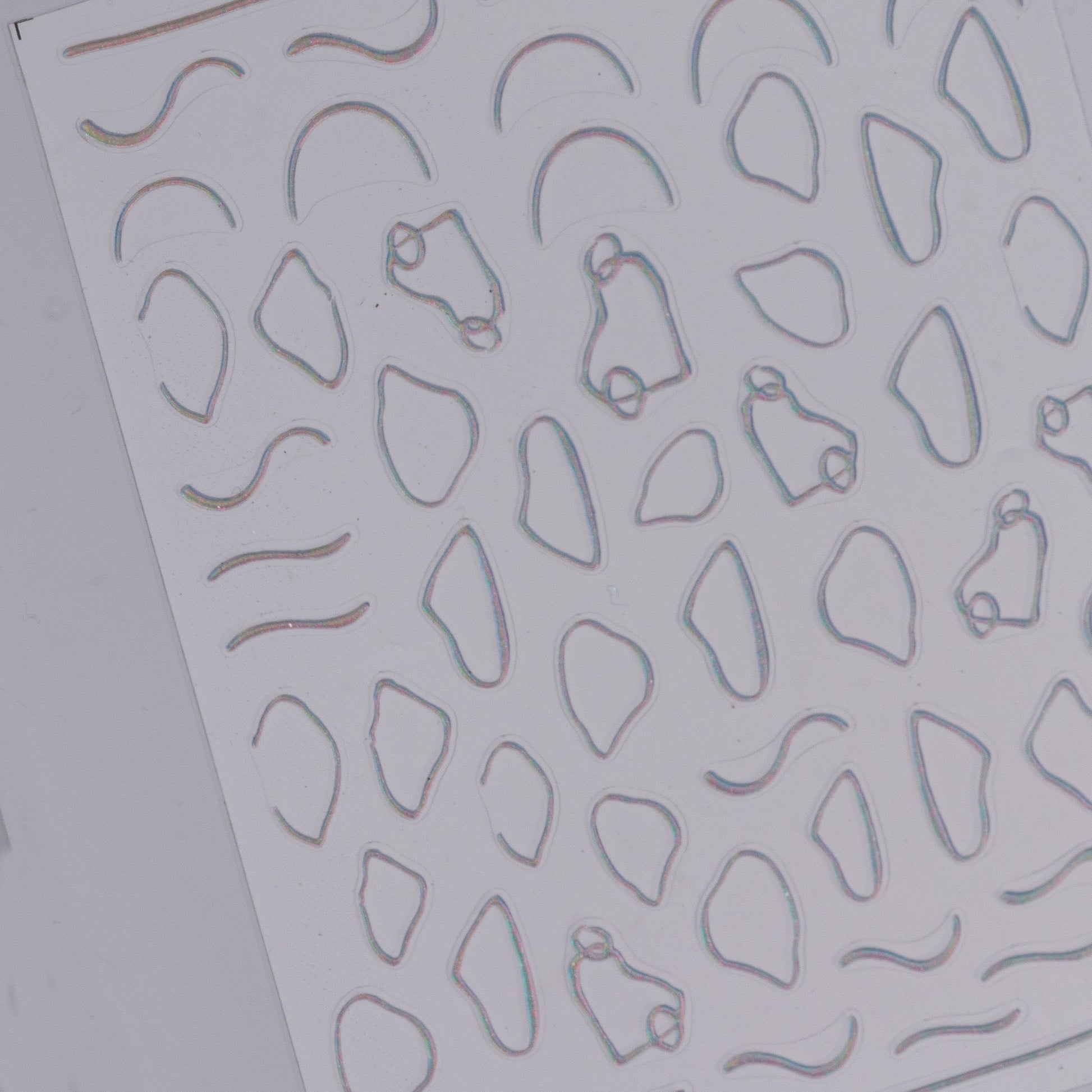 Sheet of embossed metal nail art stickerswith various geometric cutouts on a gray background