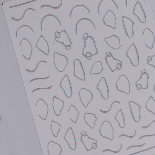 Sheet of embossed metal nail art stickerswith various geometric cutouts on a gray background