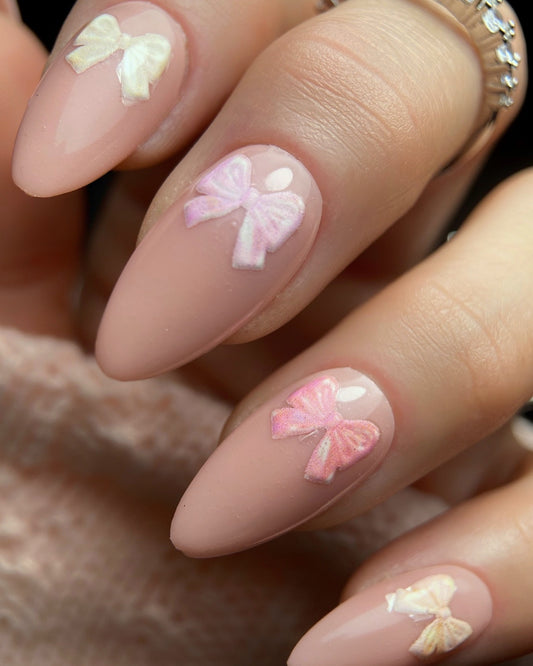 Nails with pink bow designs on a neutral background