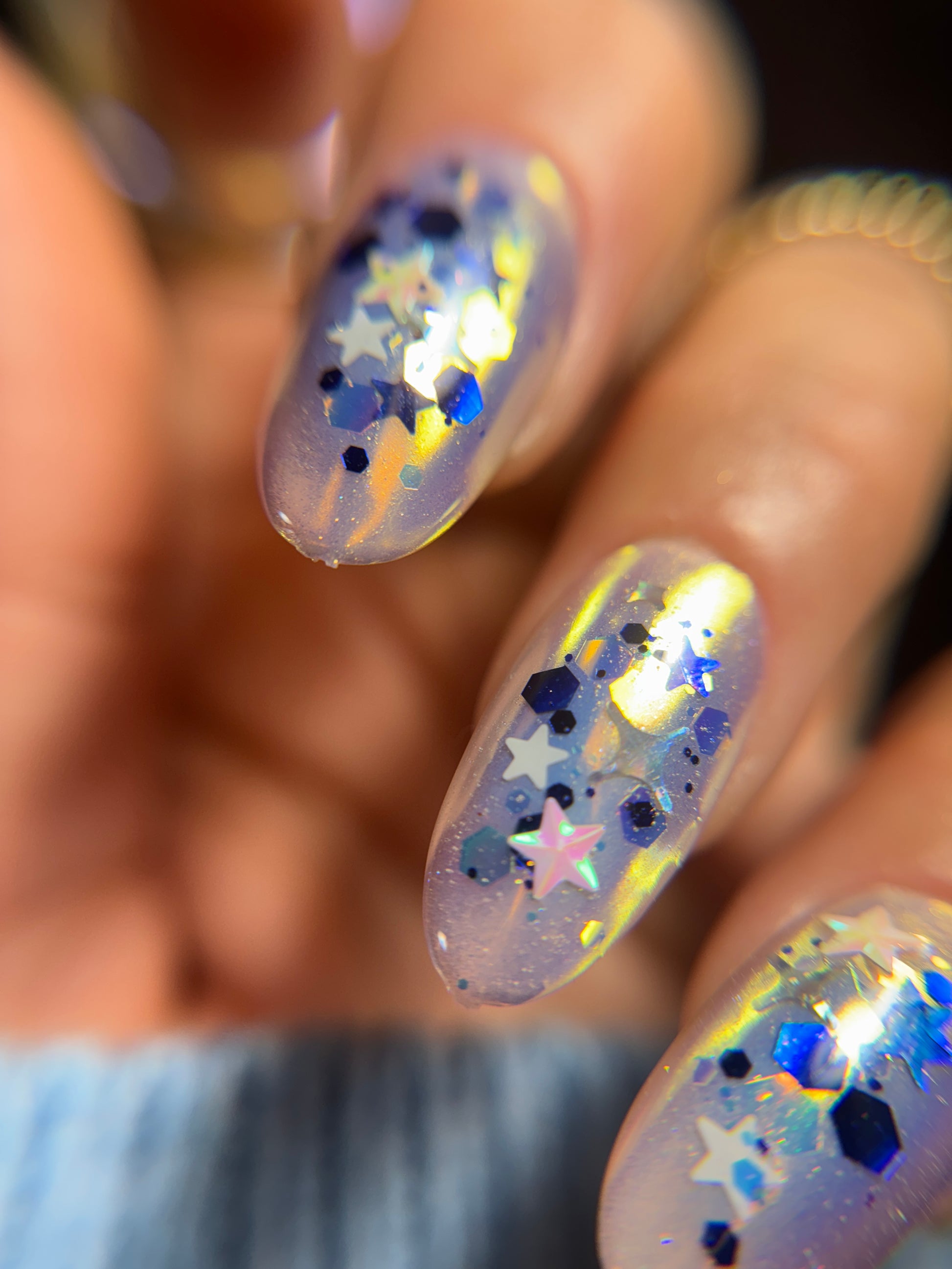 Close-up of nails with a glittery, starry design on a blurred background