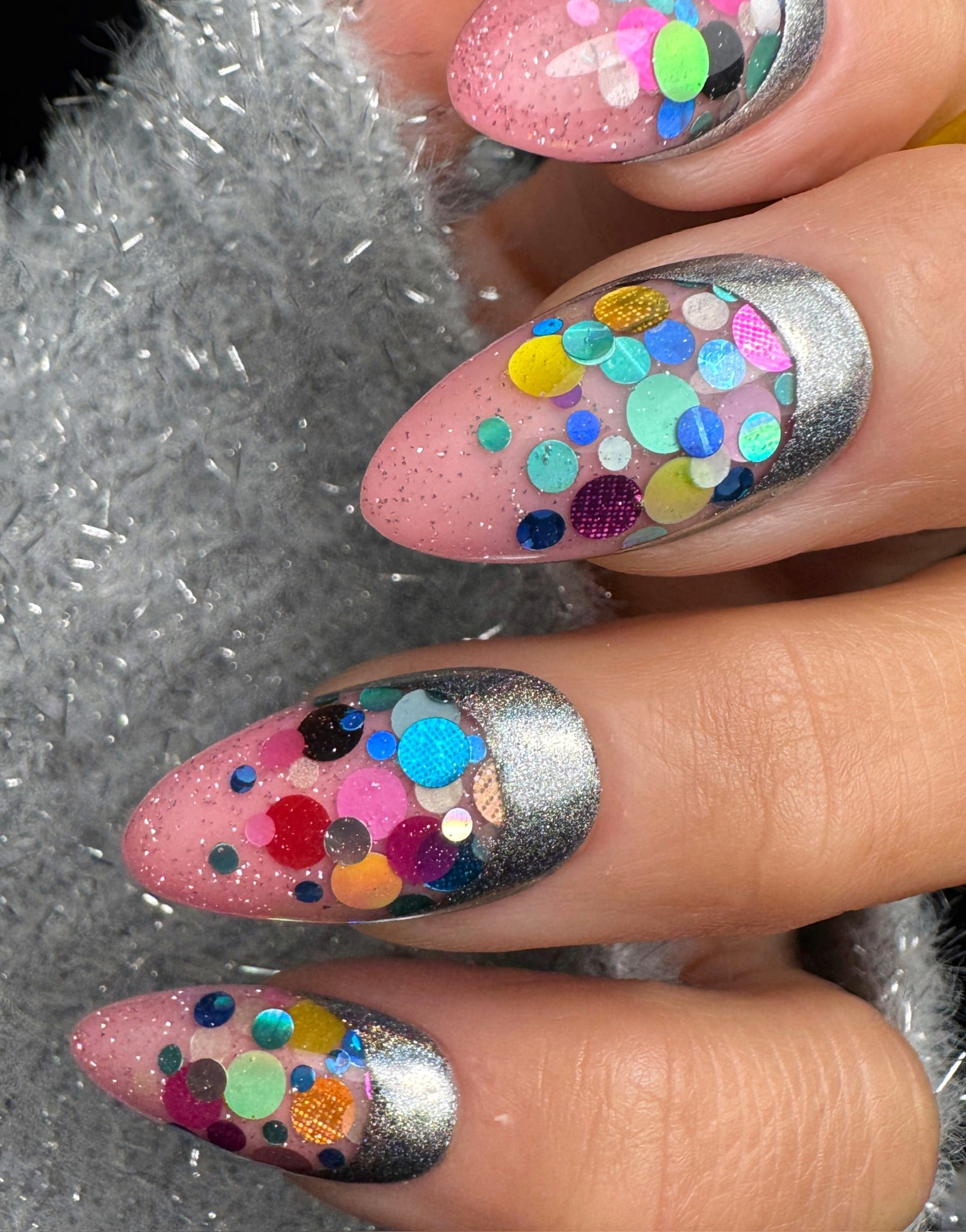 Nails with colorful confetti design on a textured background