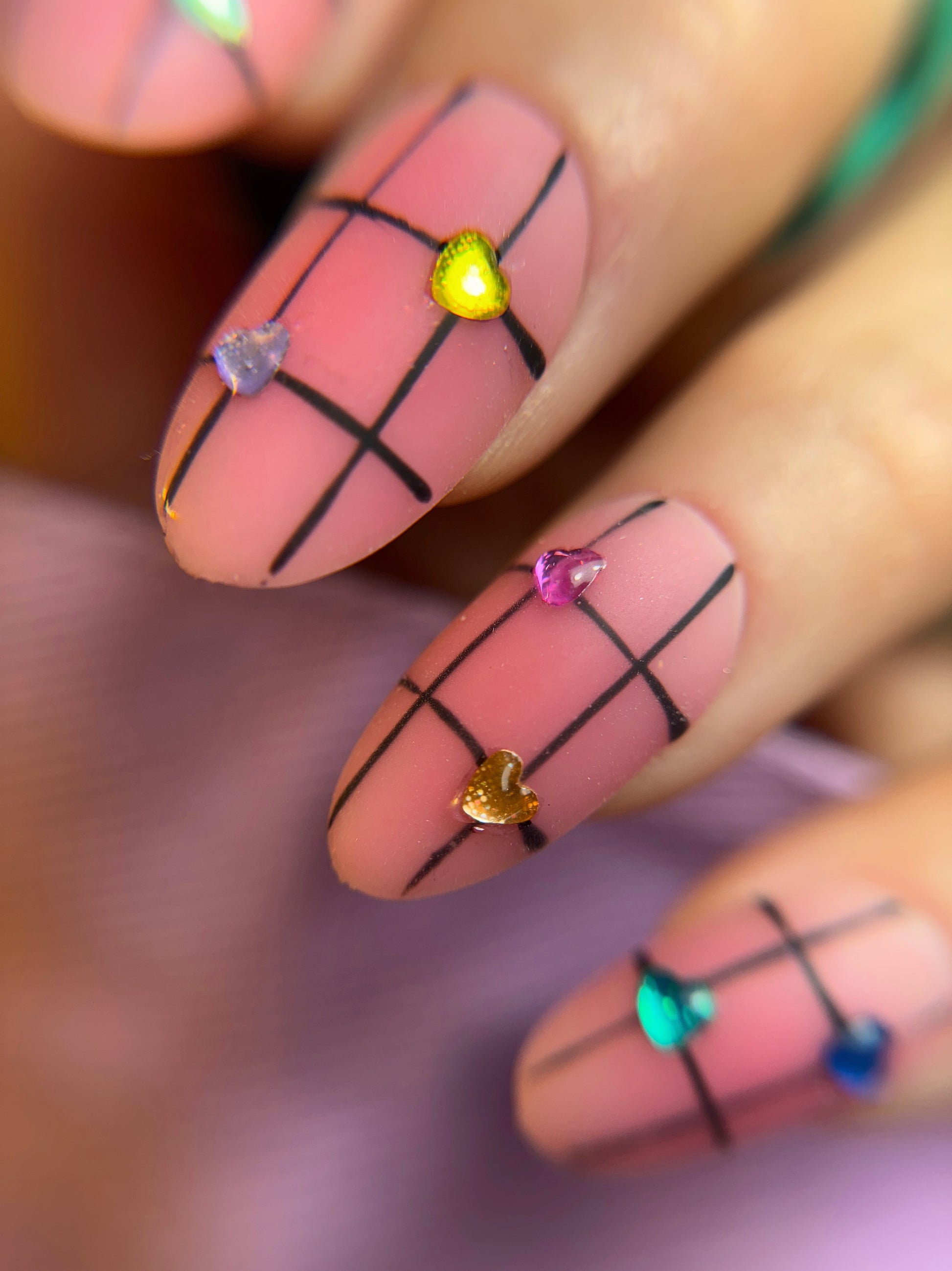 Nails with grid design and colorful hearts on a blurred background