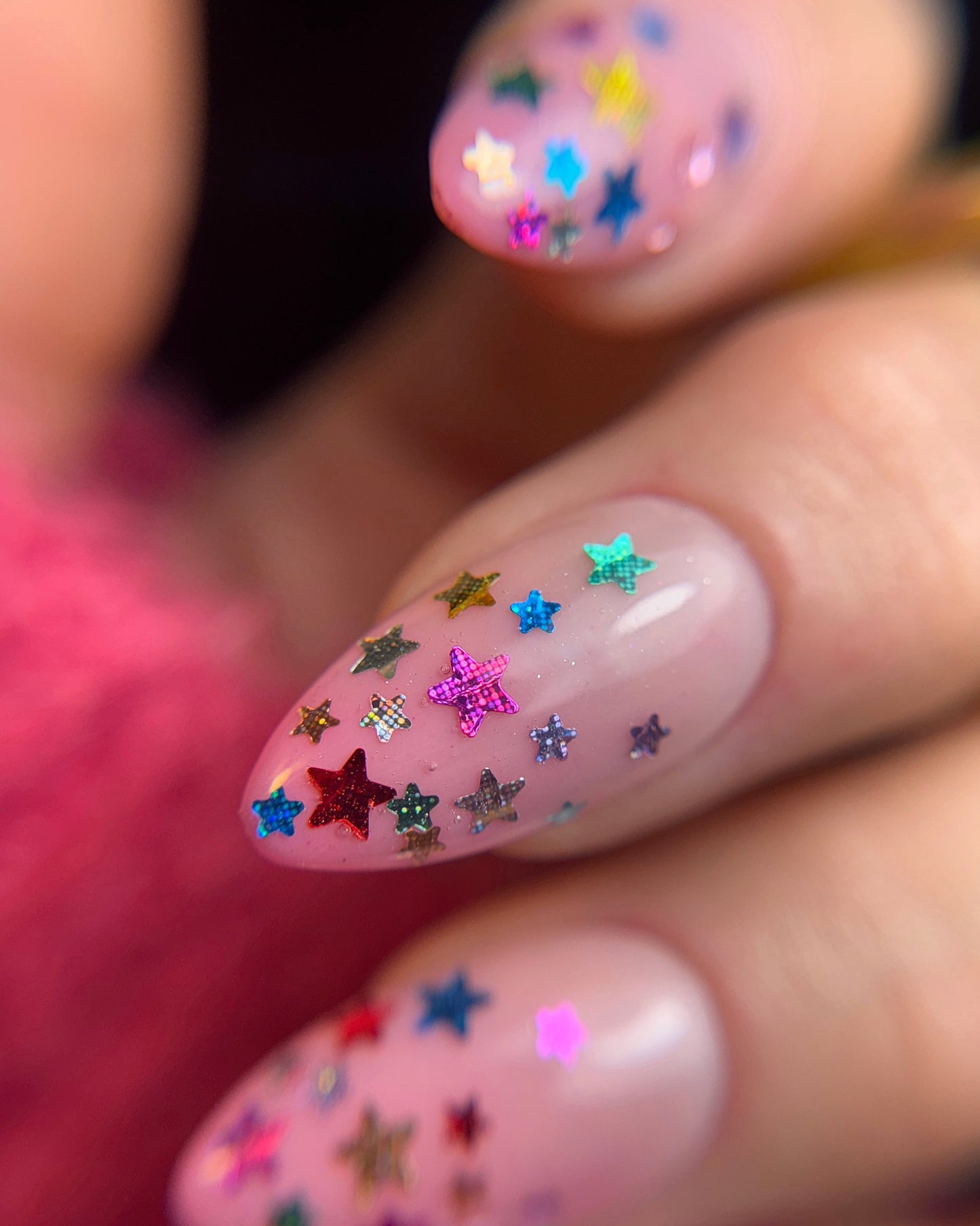 Nails with colorful star-shaped glitter on a blurred background