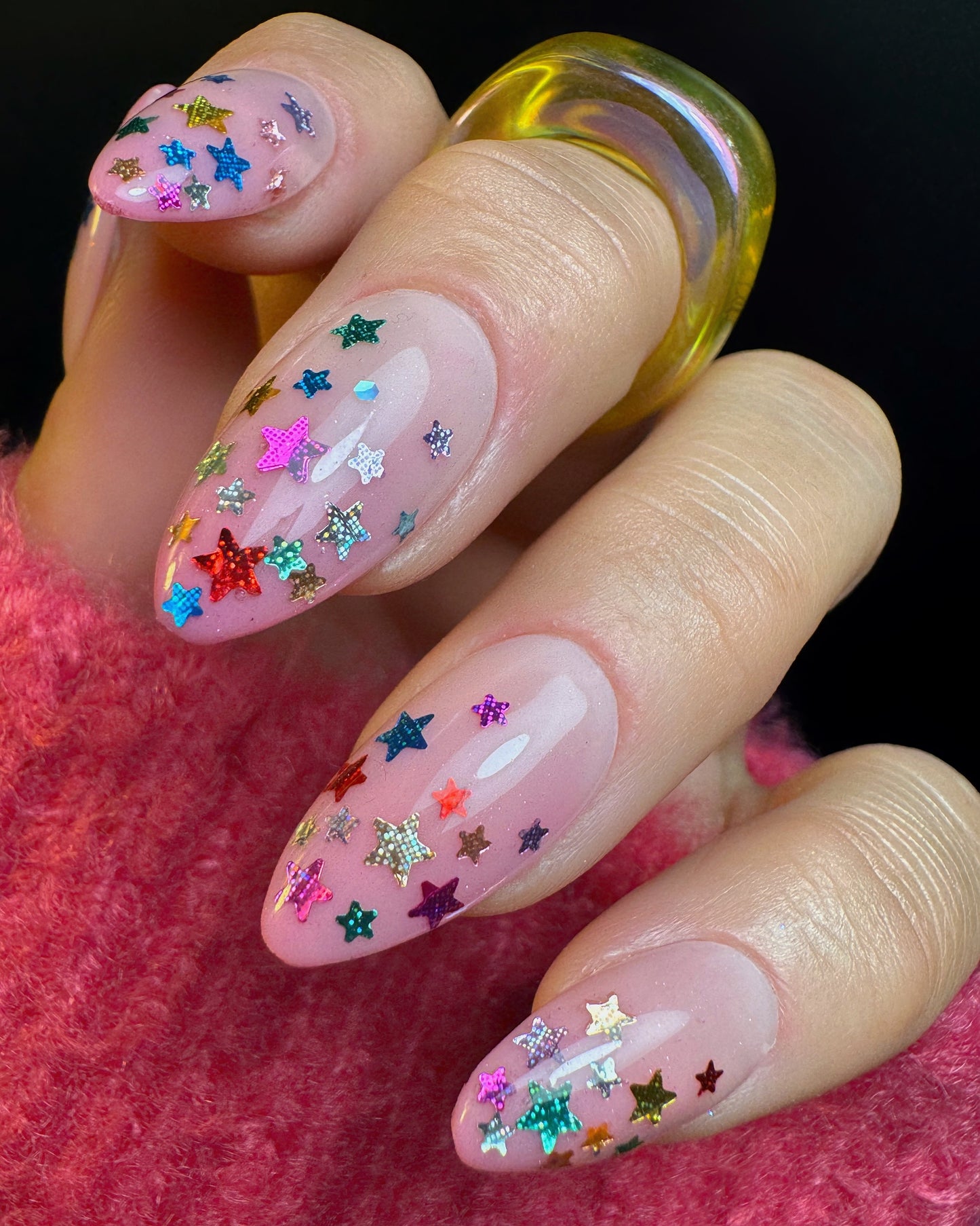 Nail art with colorful star sequins on a pink background