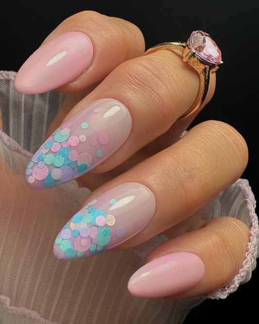 Nail art with pink and blue confetti design on a black background