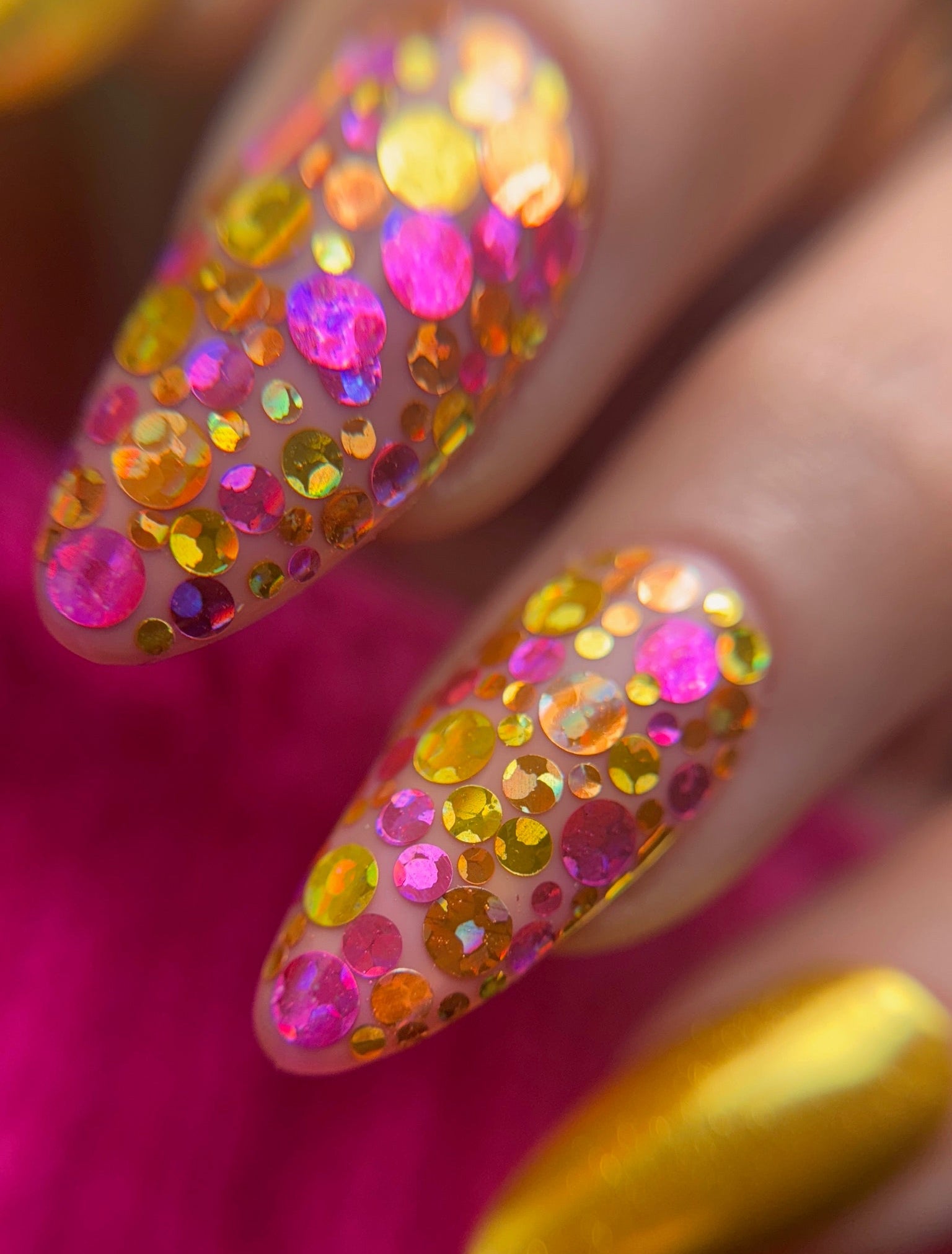 Nails with colorful glittery design on a pink background