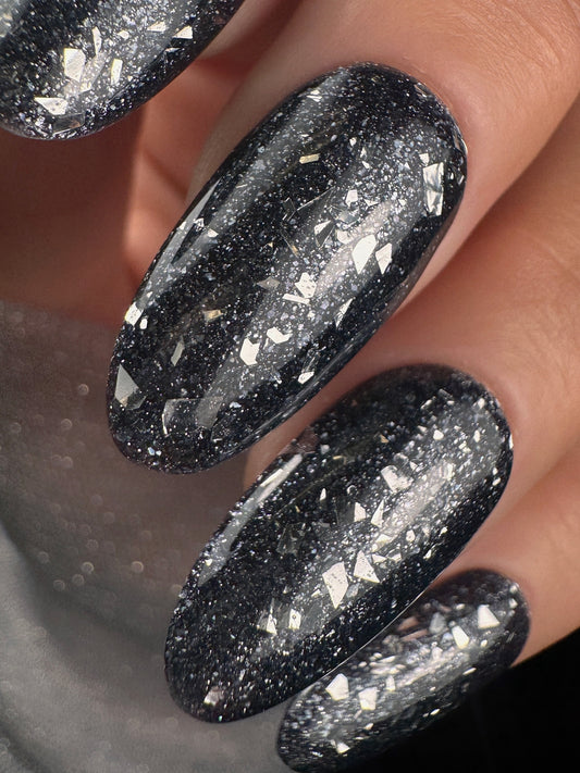 Close-up of black glittery nails on a neutral background