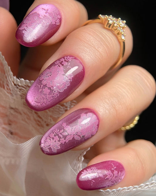 Hand in lace sleeve with ring and pink floral design on nails. 