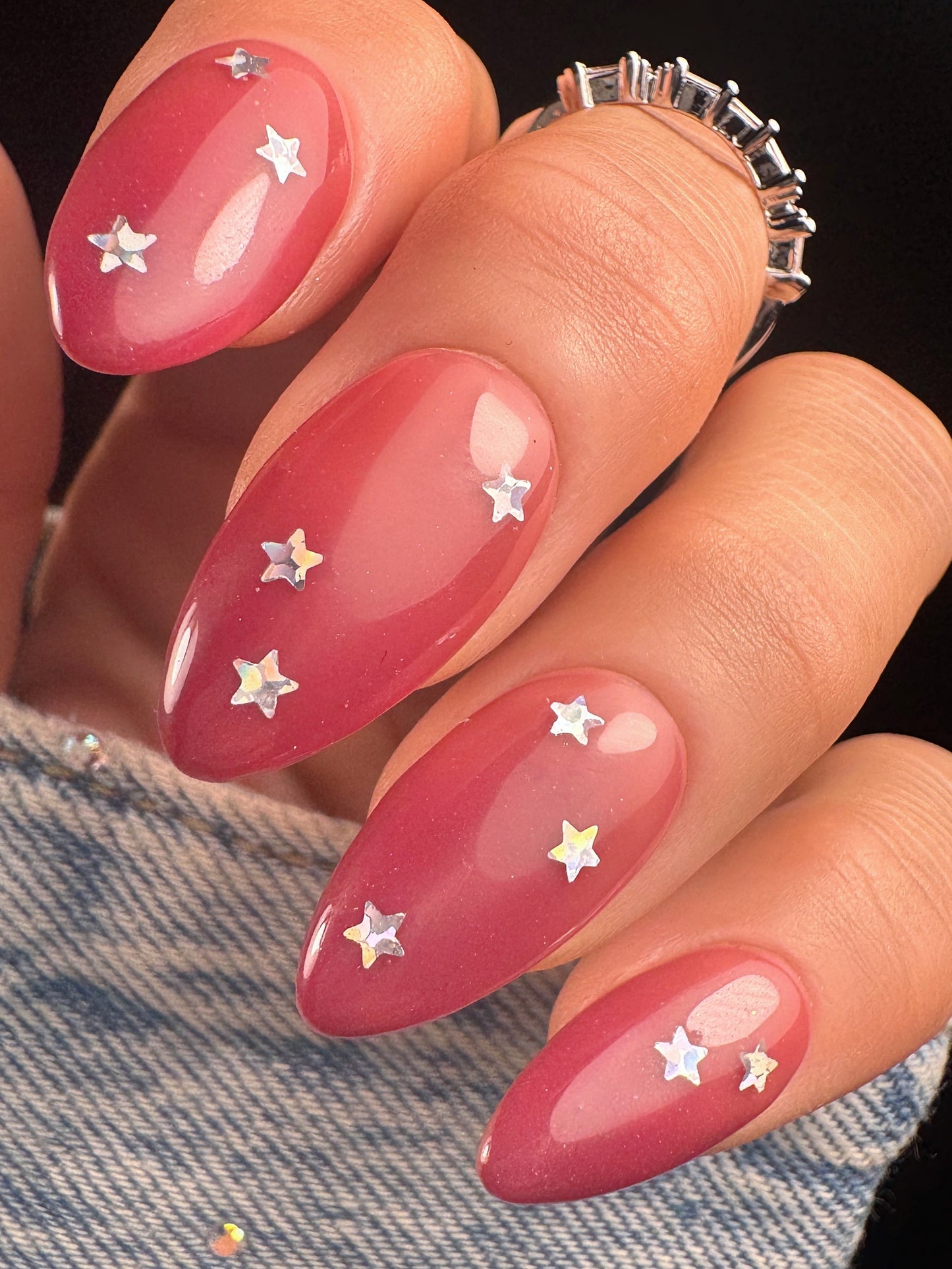 Nails with red gradient design and star decorations on a denim background