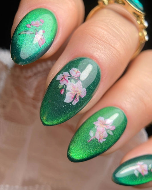 Close-up of hand with green nails and floral detail. 