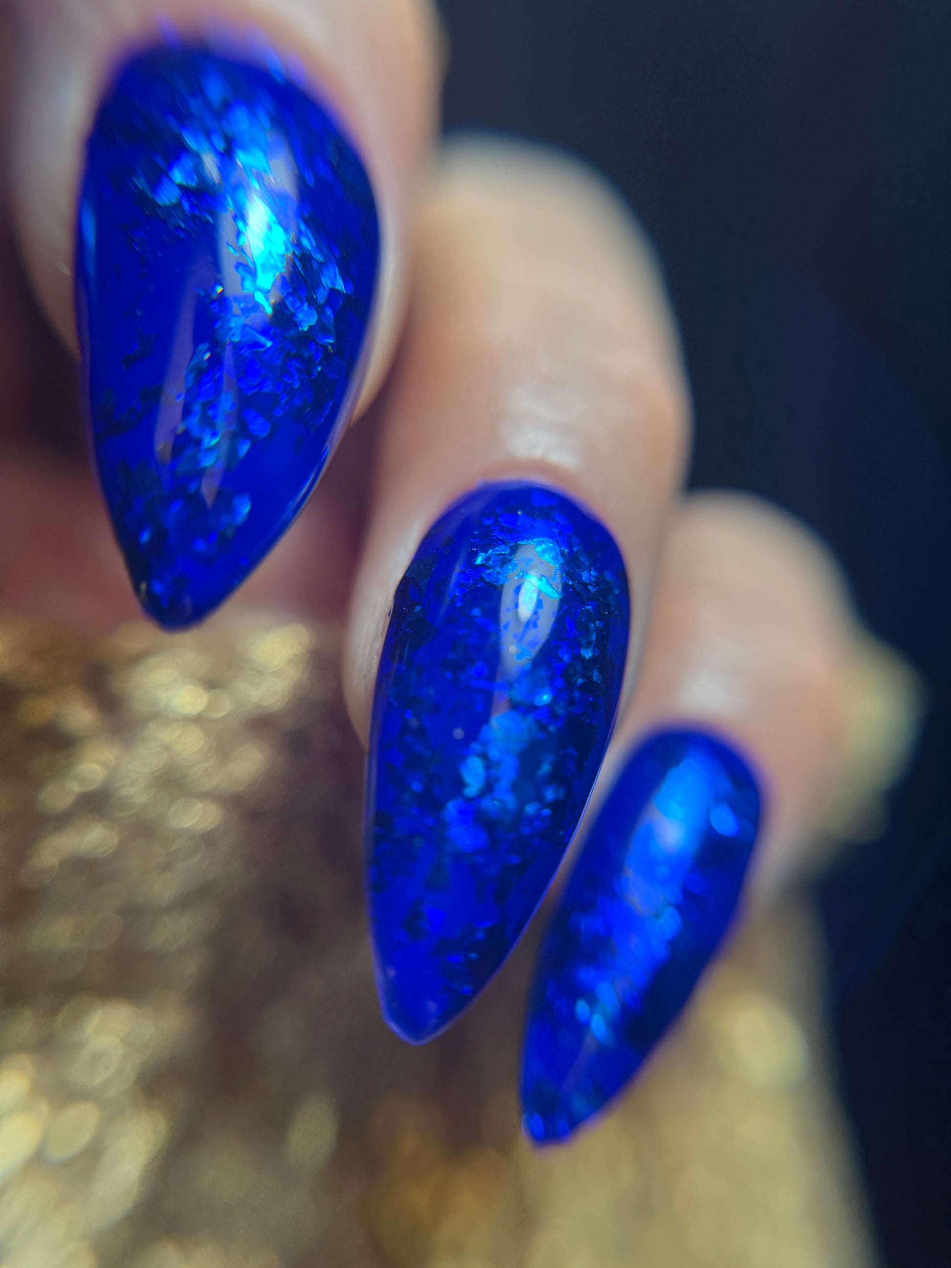 Close-up of a hand with blue glittery nail design on a blurred background