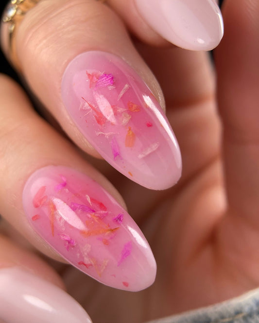 Close-up of pink nail polish with floral design on a blurred background