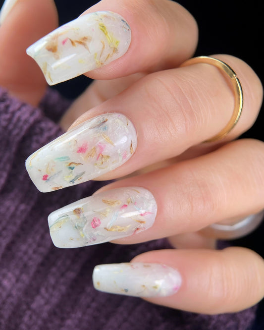 Close-up of a hand with decorative nail art featuring small colorful flowers.