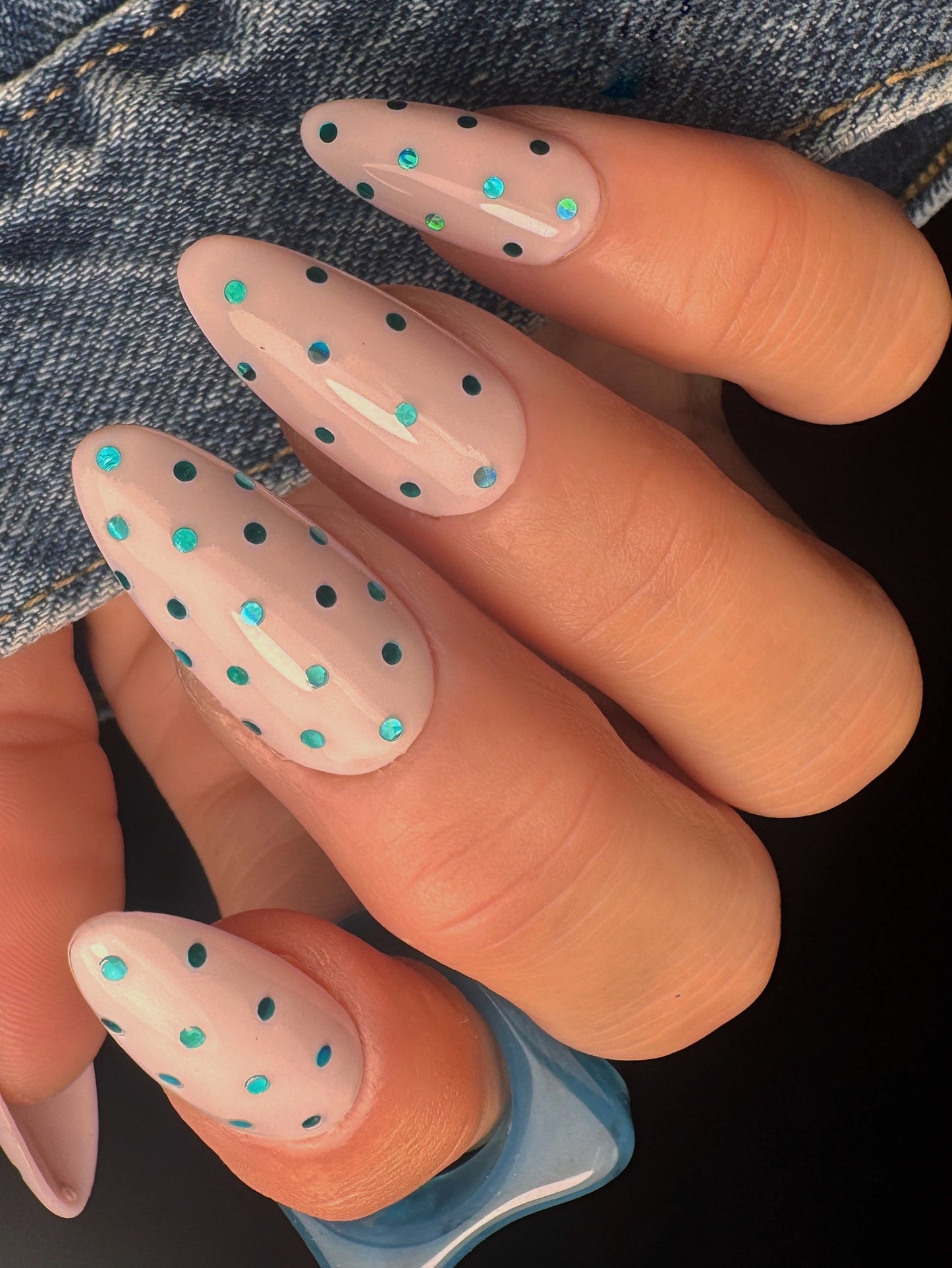 Nails with polka dot design held against a denim background