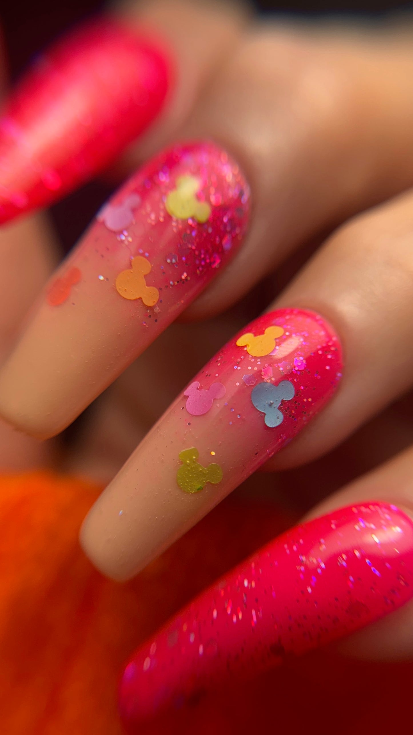 Nails with colorful designs and glitter on a blurred background