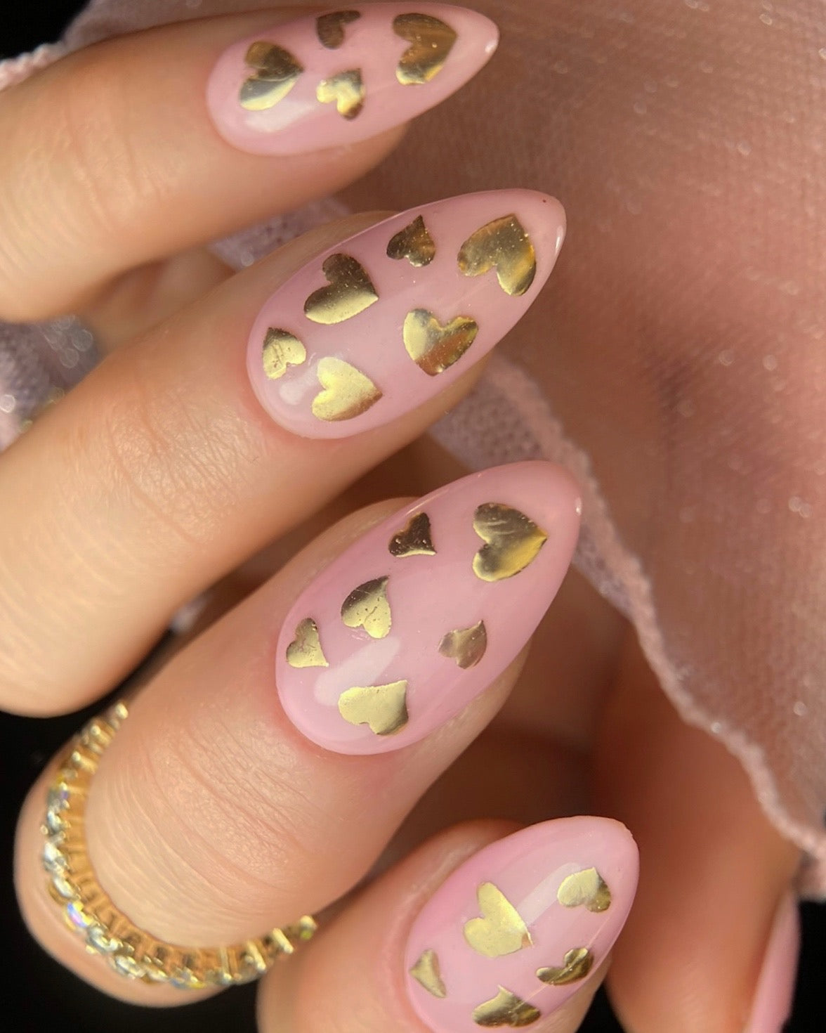 Pink nails with gold heart design.