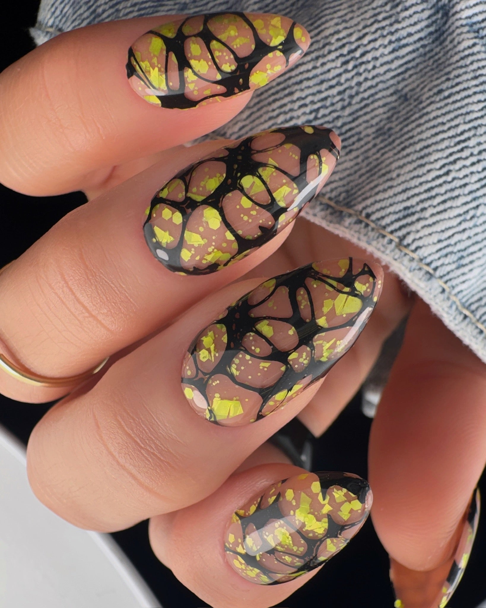 Nails with a graphic web design in yellow and black on a neutral background