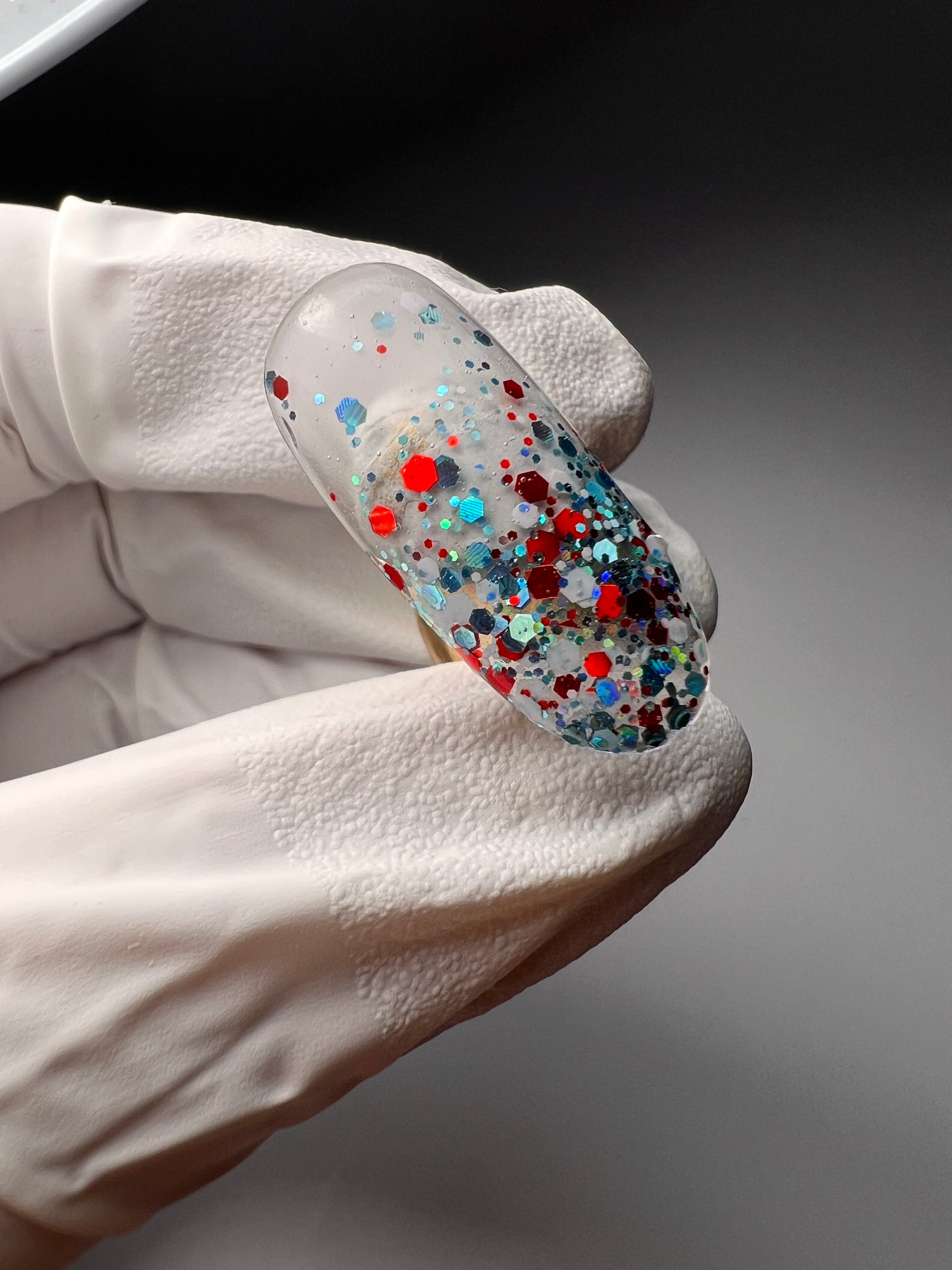 Still of hand holding glitter nail tip. 