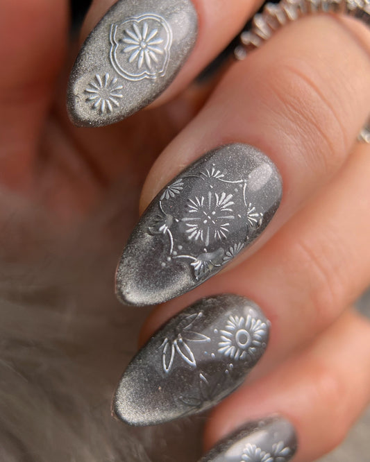 Nails with silver floral designs on a blurred background