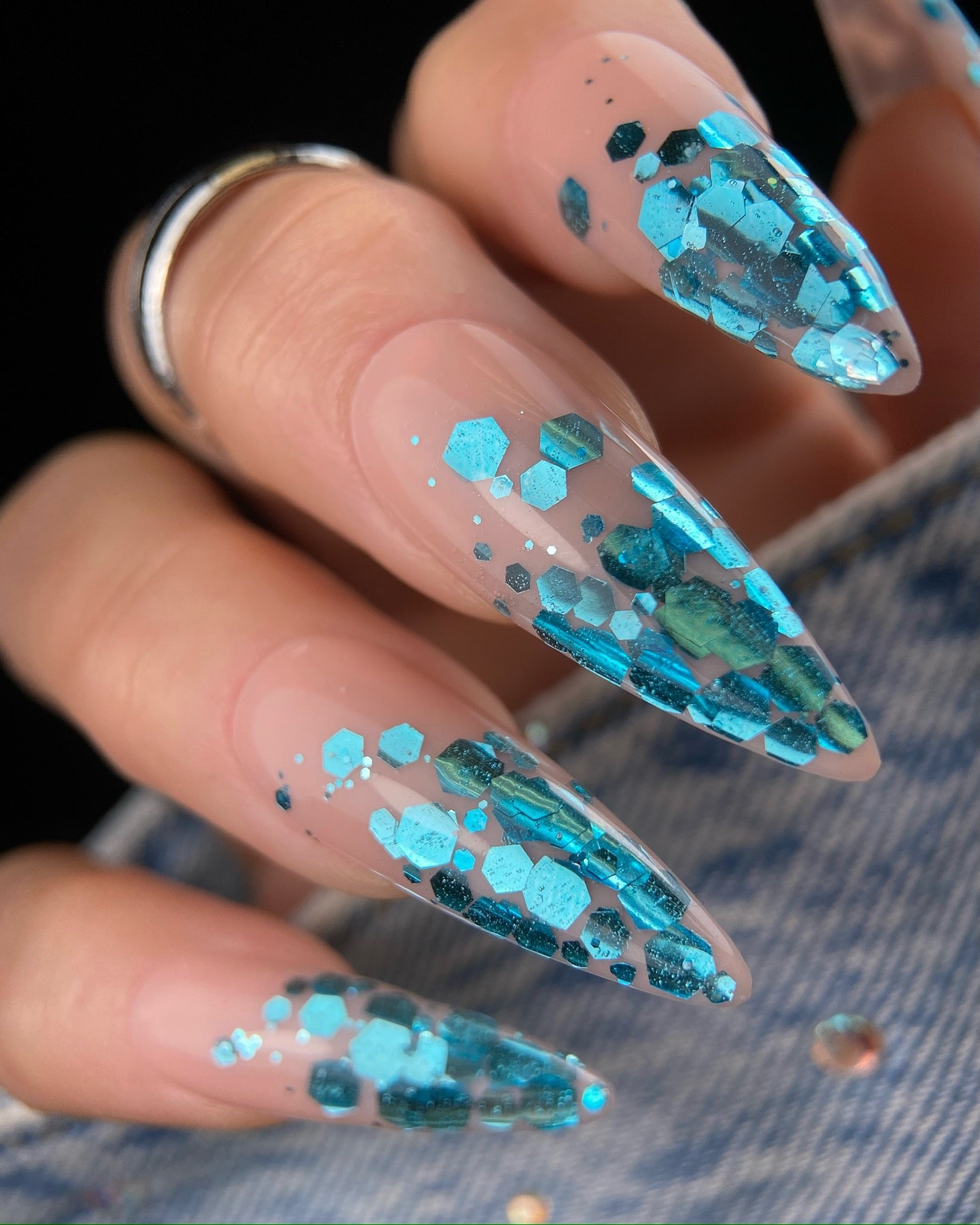 Nails with blue glitter design on a dark background