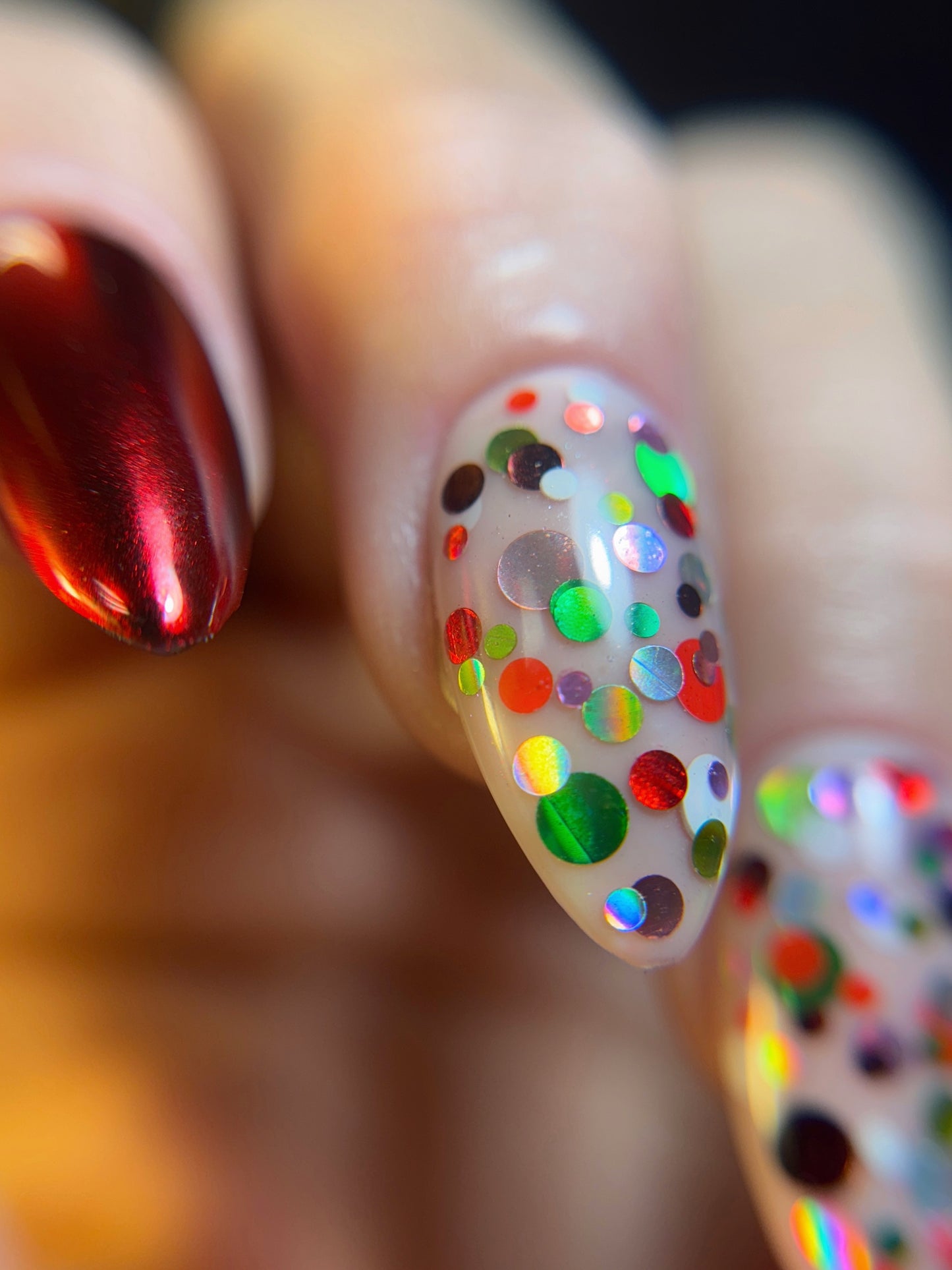Close-up of a hand with colorful polka dot nail art on a blurred background