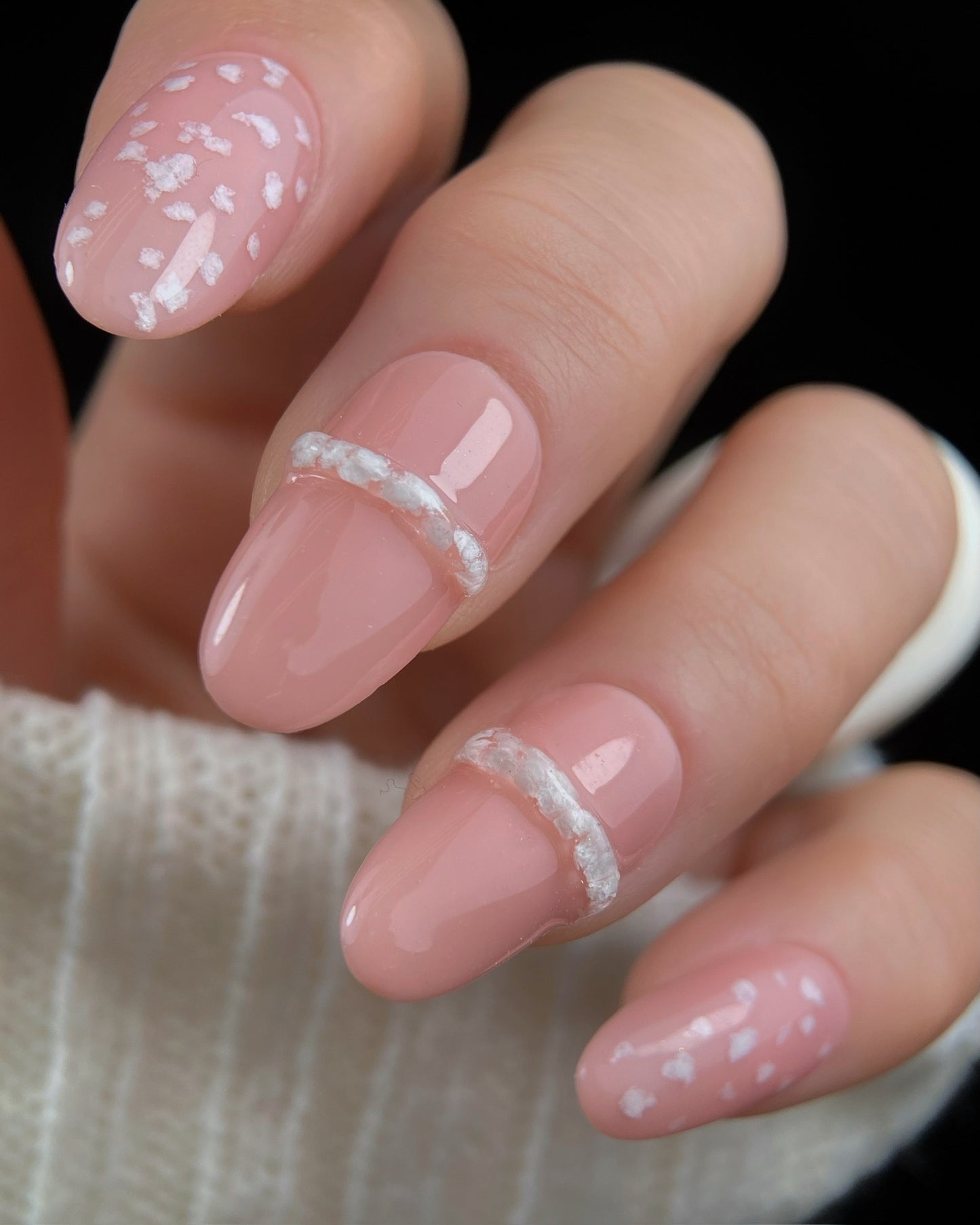 Close-up of a hand with pink nail polish and decorative elements.