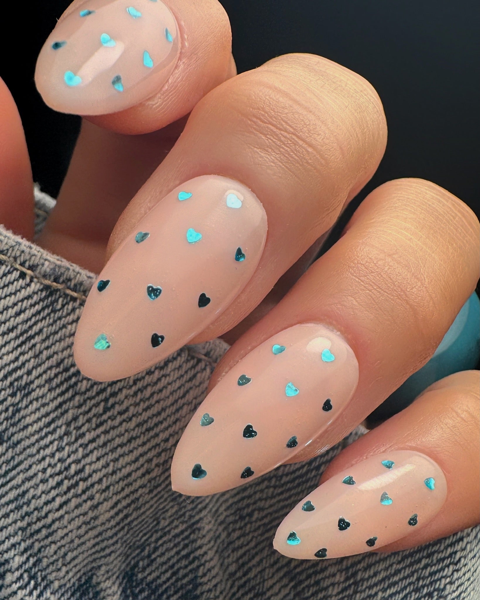 Nails with heart-shaped glitter designs on a dark background