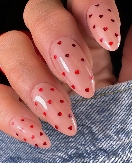 Nails with red heart designs on a denim background