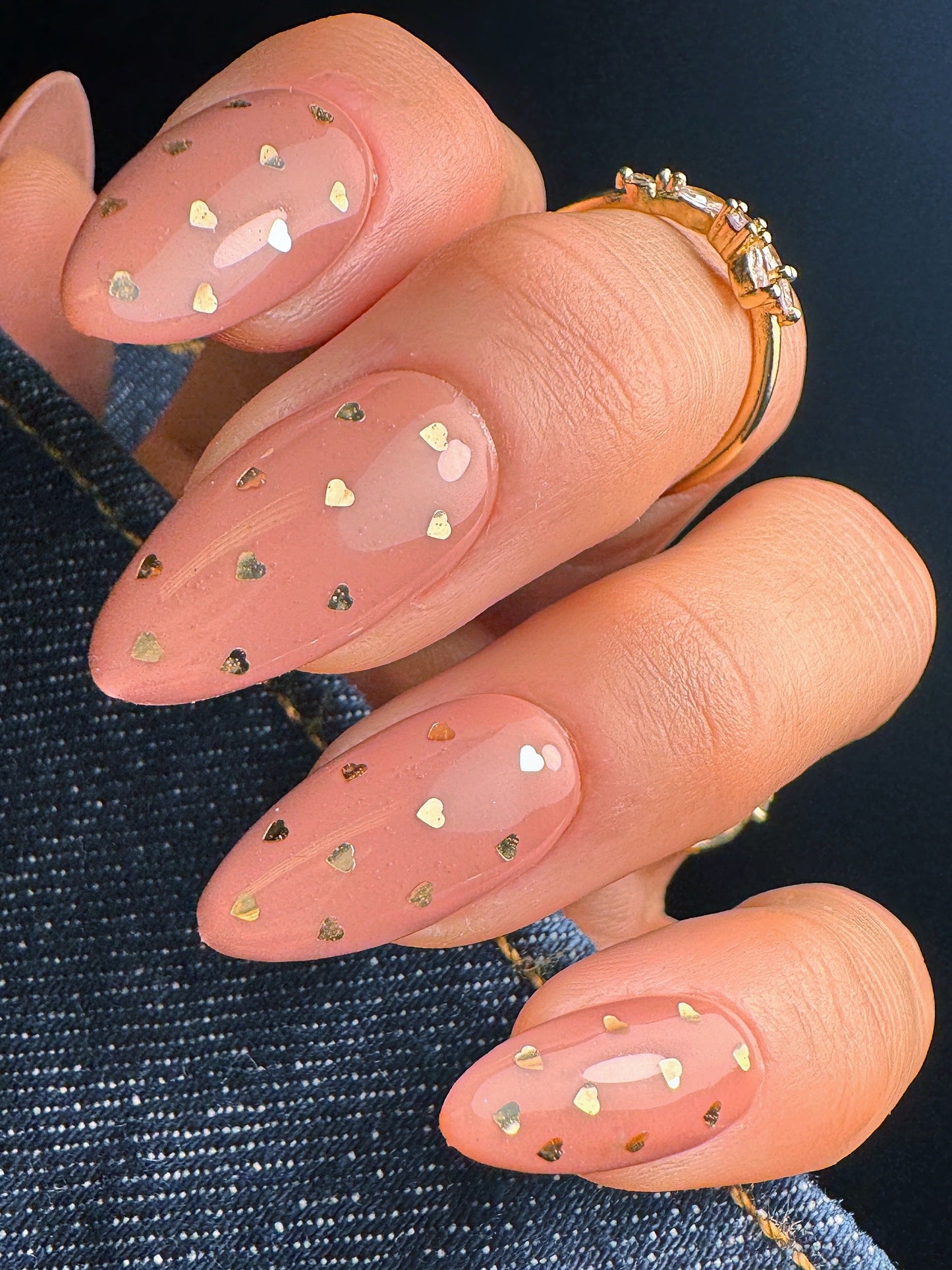 Nail art with gold heart decorations on a dark background