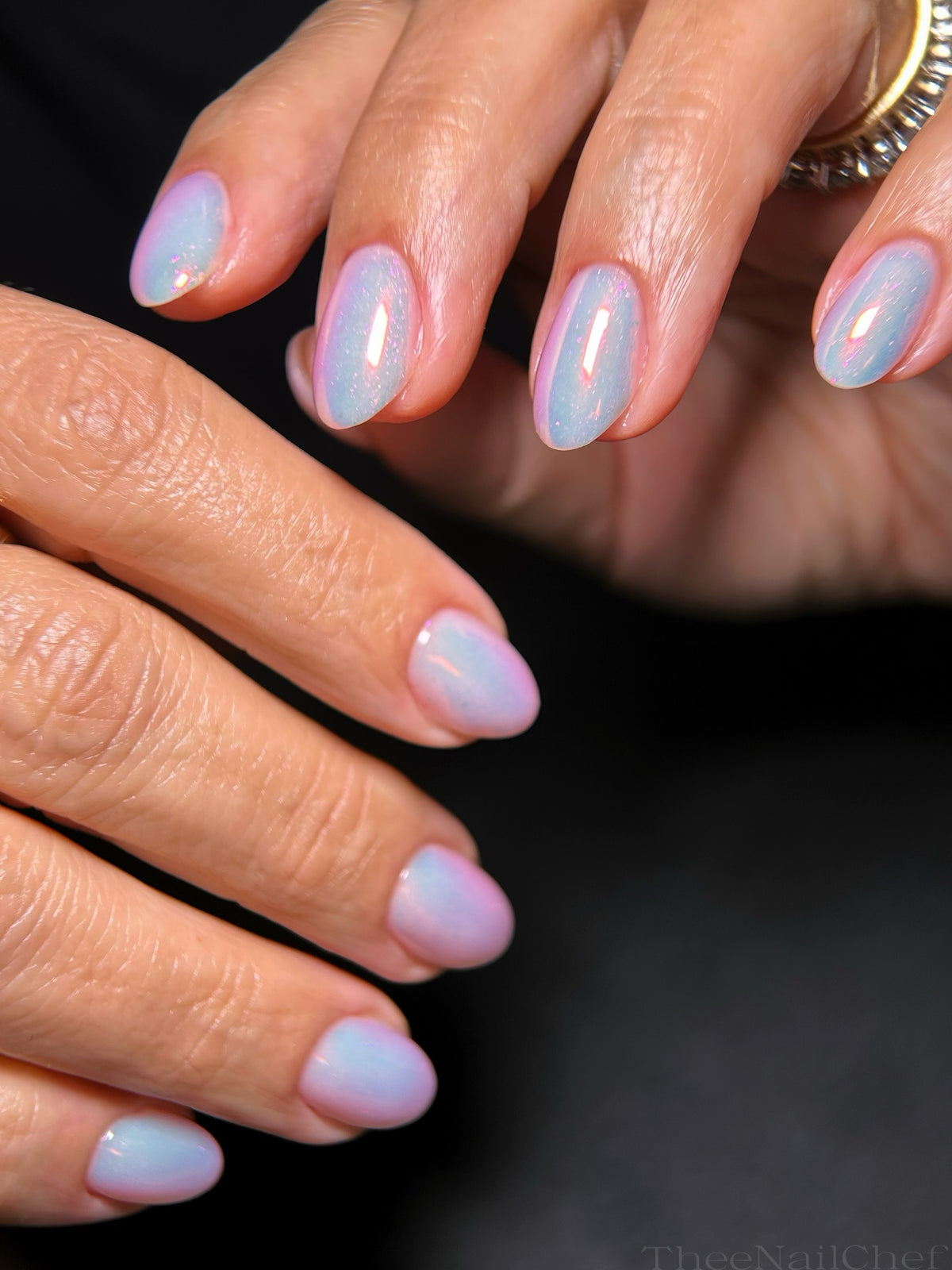 Soft blue manicure by Jennie Guthrie using Vacation Nail Shop Coral Flare Chrome, with a sheer iridescent coral-pink glow on short natural nails.