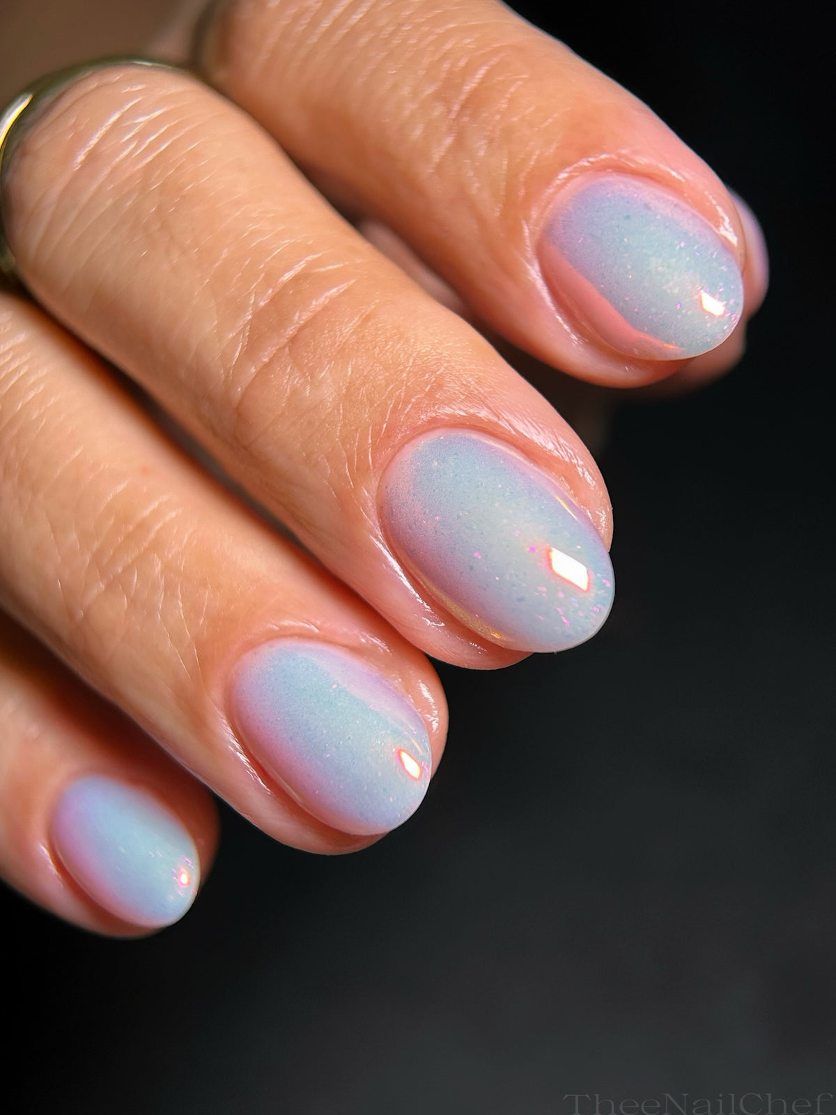 Iridescent blue manicure by Jennie Guthrie using Vacation Nail Shop Coral Flare Chrome, showing its soft coral-pink shift across natural almond nails.
