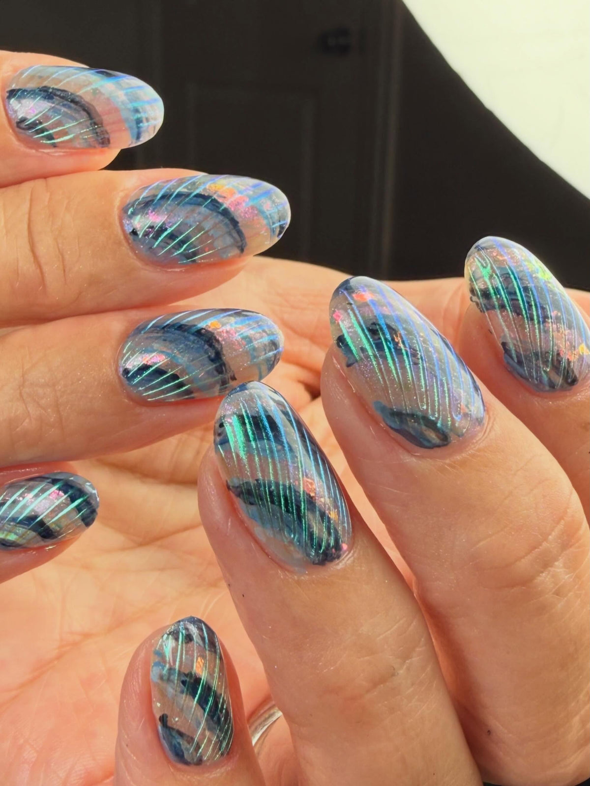 Sheer seashell-inspired nail art by Dylan Pritchard using Vacation Nail Shop Ethereal Chrome, with translucent blue details, iridescent flakes and fine curved chrome lines.