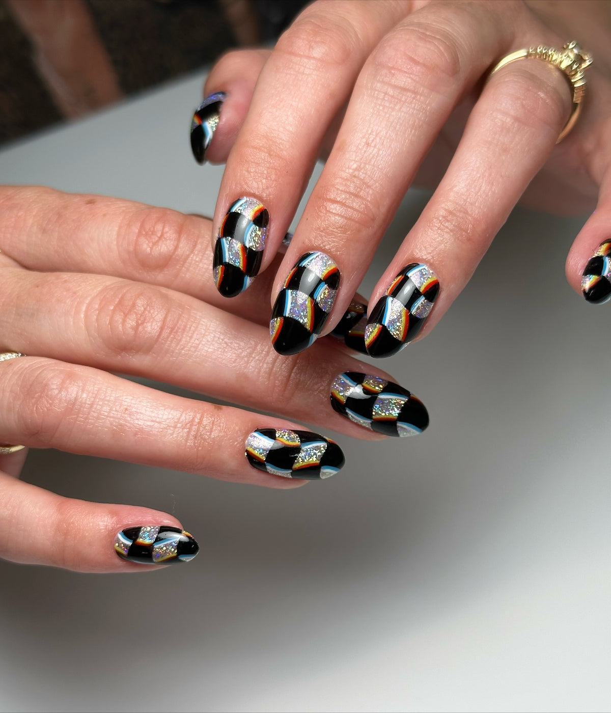 Black checkerboard nail art by Cindy Trieu featuring Vacation Nail Shop Mega Holo Chrome, with sparkling holographic sections and colorful accent stripes.