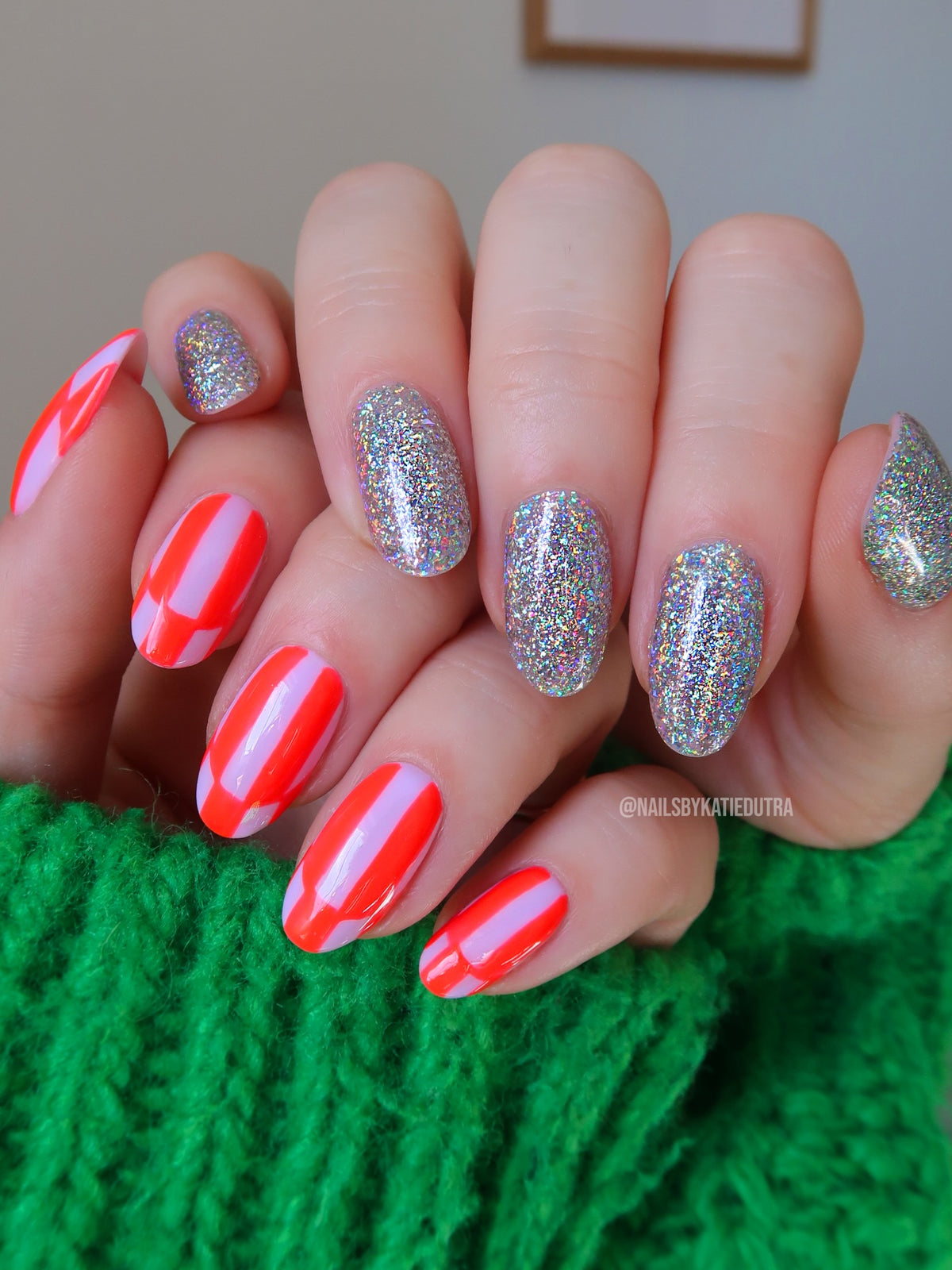 Manicure by nail artist Katie Dutra featuring Vacation Nail Shop Mega Holo Chrome on almond-shaped nails, paired with glossy neon coral and pale pink striped nail art.