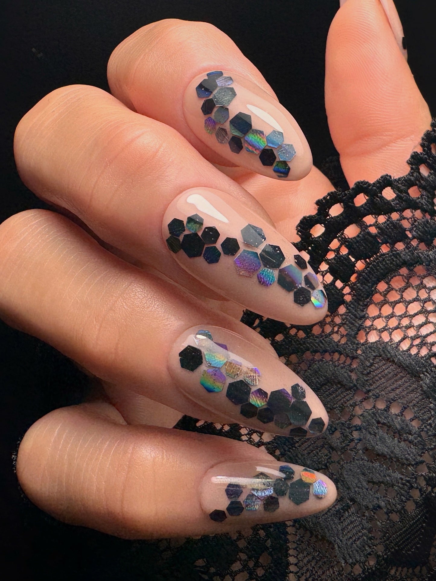 Nails with hexagonal glitter design on a black lace background