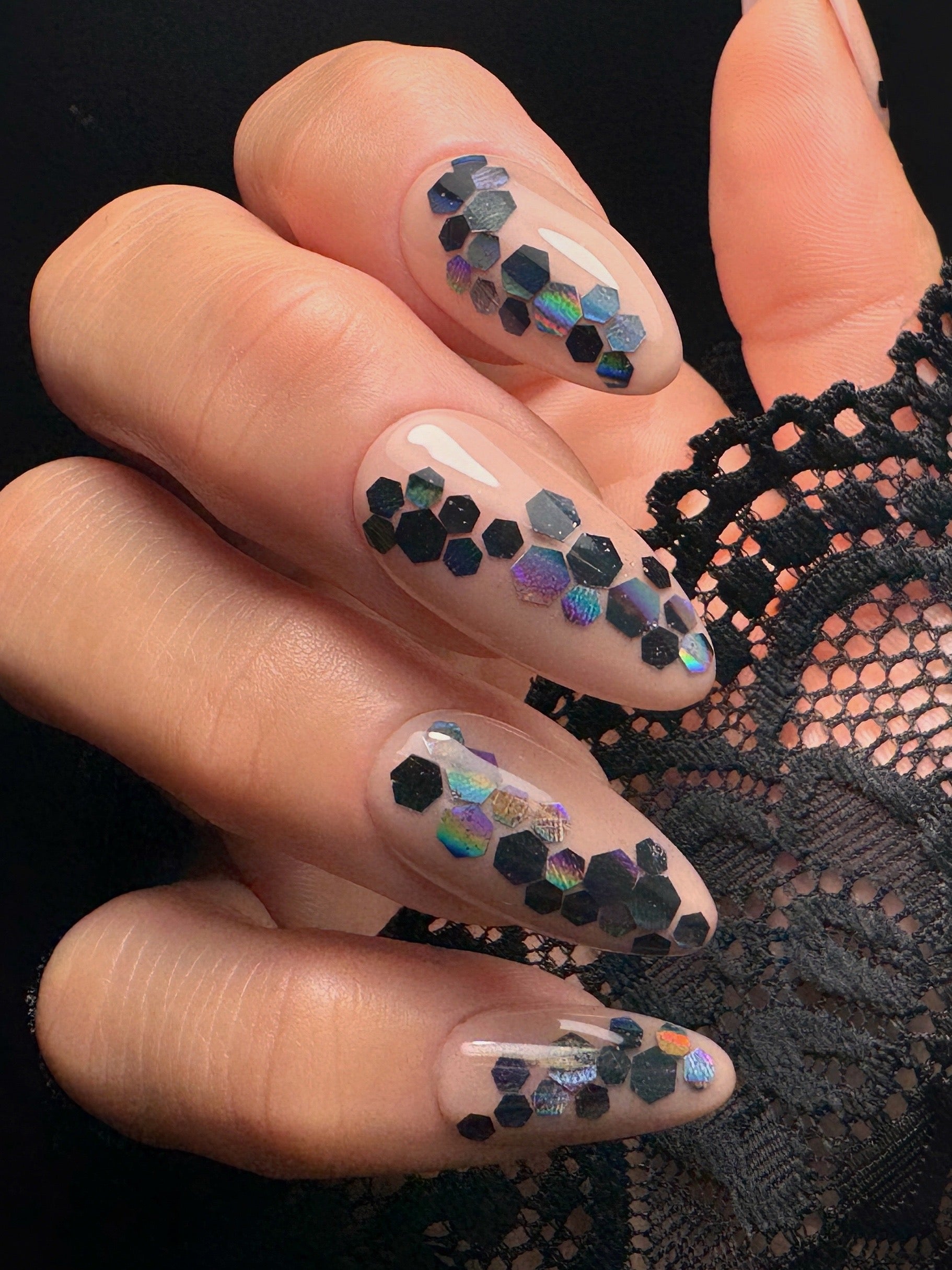 Nails with hexagonal glitter design on a black lace background