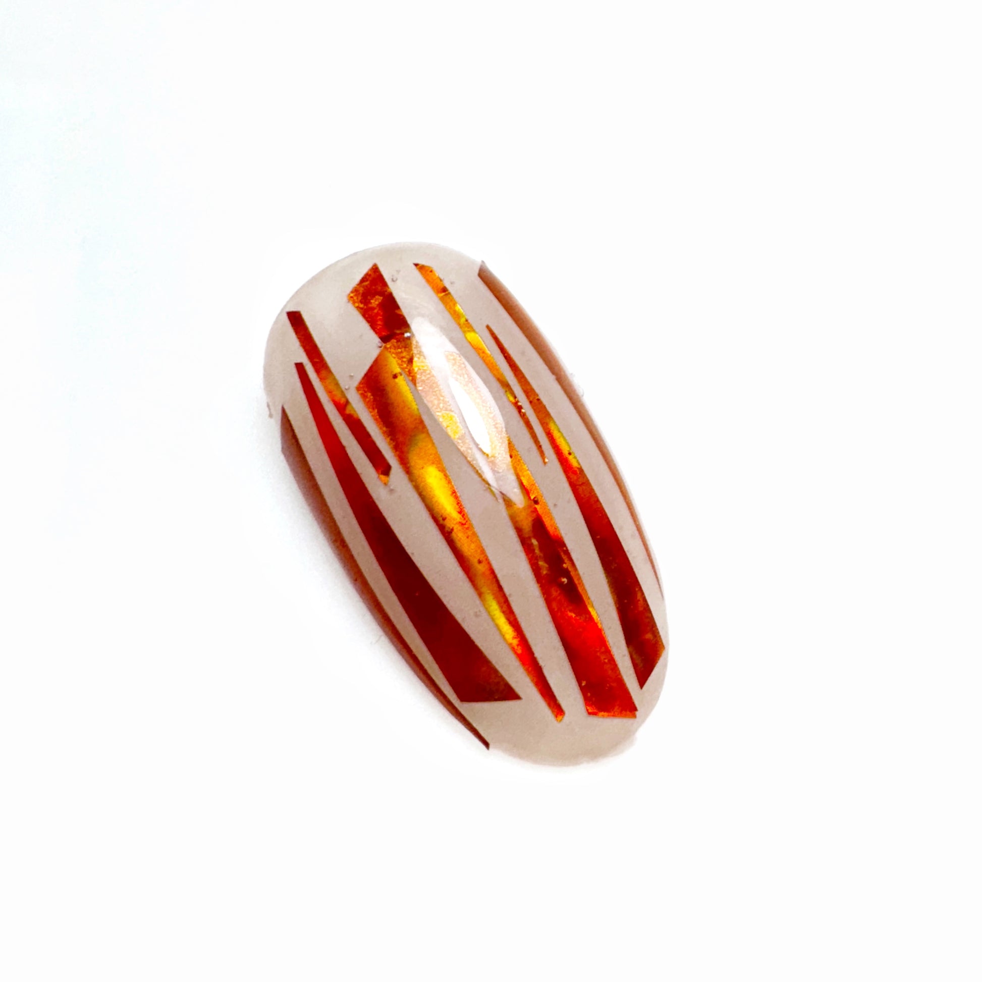 Close-up of iridescent sliced mylar on a neutral nail tip on light background