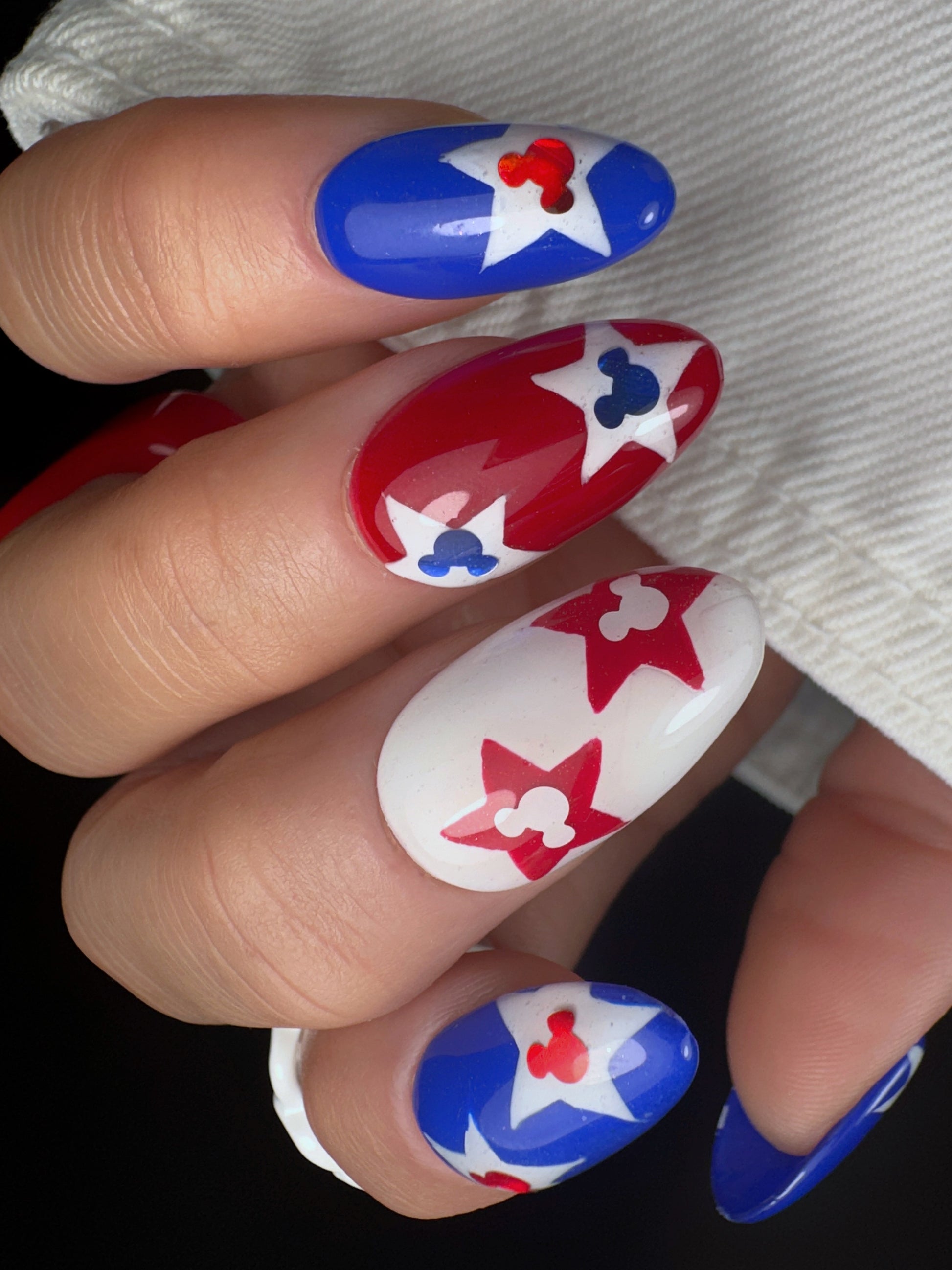 Nails with red, white, and blue star and mouse designs.