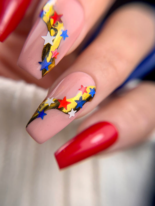 Nail art with colorful stars and red polish on a blurred background
