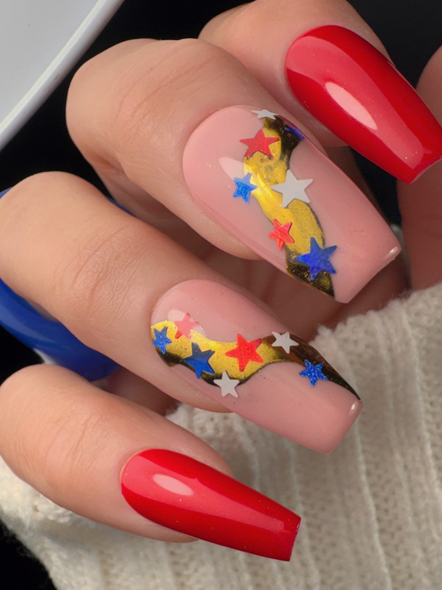 Nails with colorful star design and red polish on a neutral background