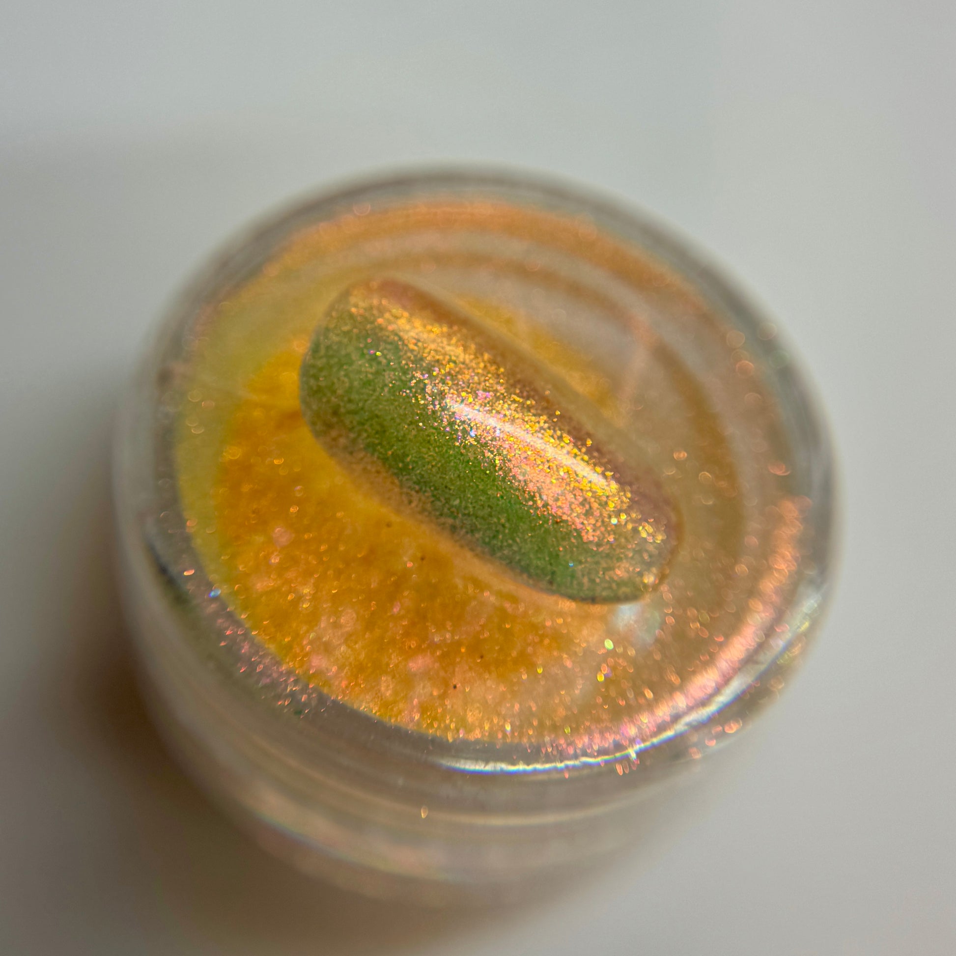 close up of iridescent colored bail tip resting on transparent jar on blurred background