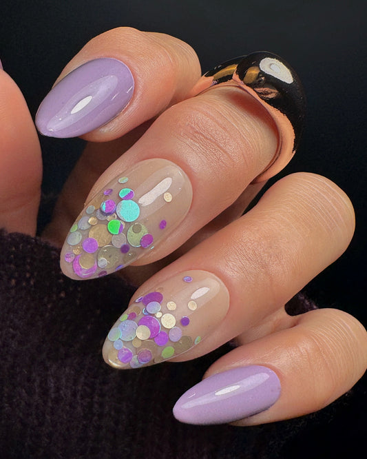 Close-up of a hand with decorative nails featuring purple and gold and multicolored glitter.