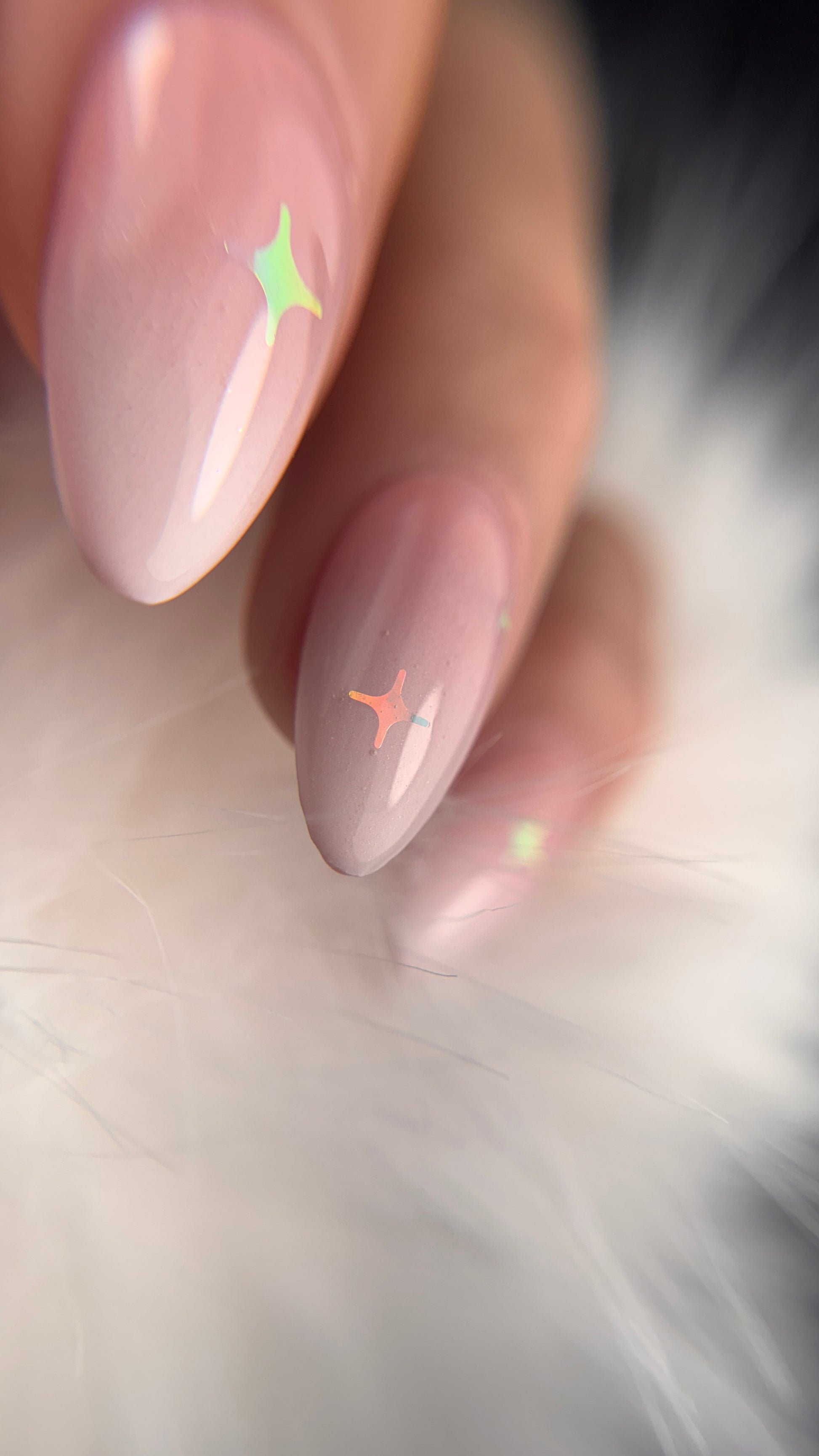 Close-up of a hand with pink nail polish on a soft, blurred background