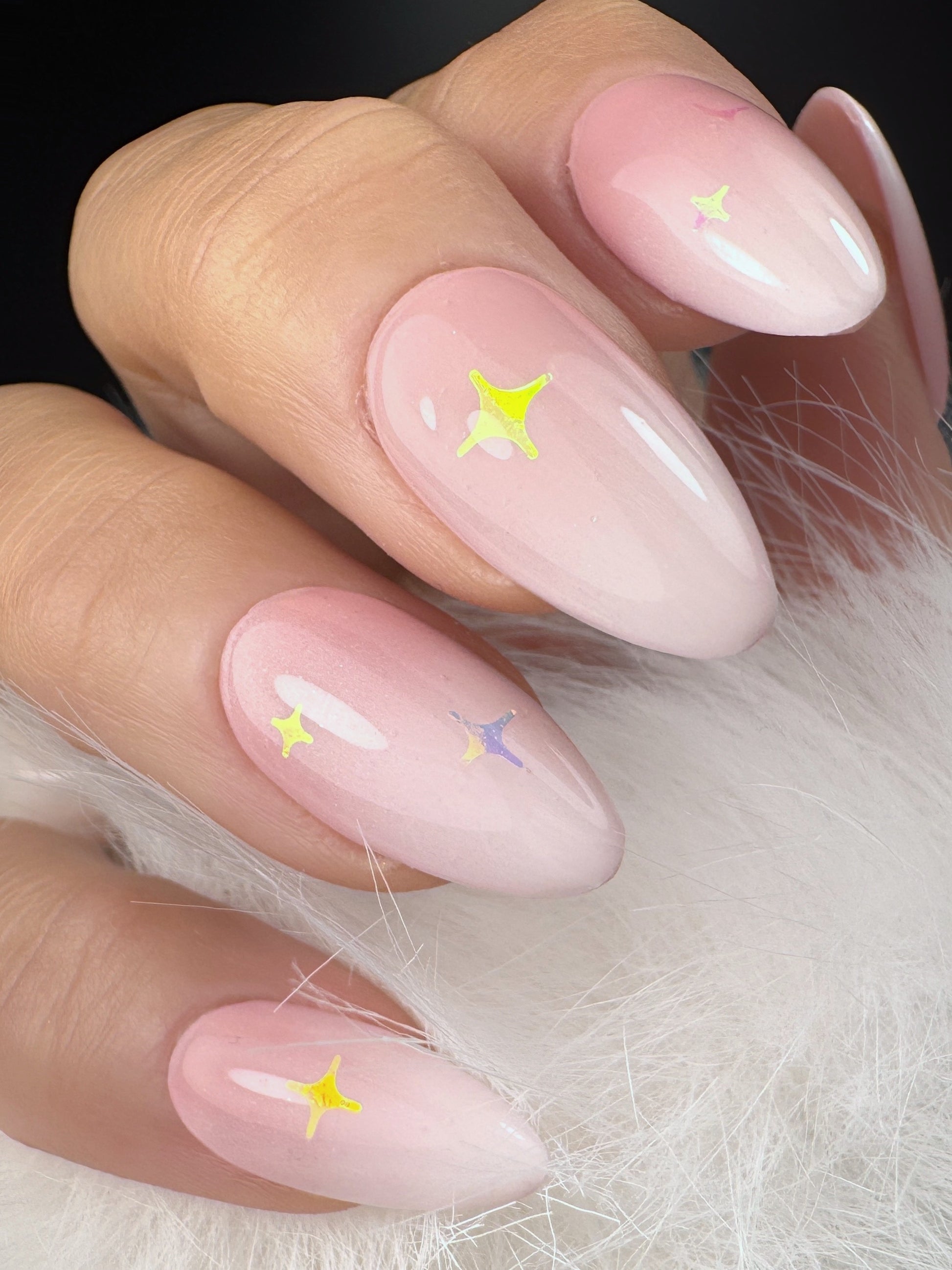 Pink nails with star designs on a white fur background