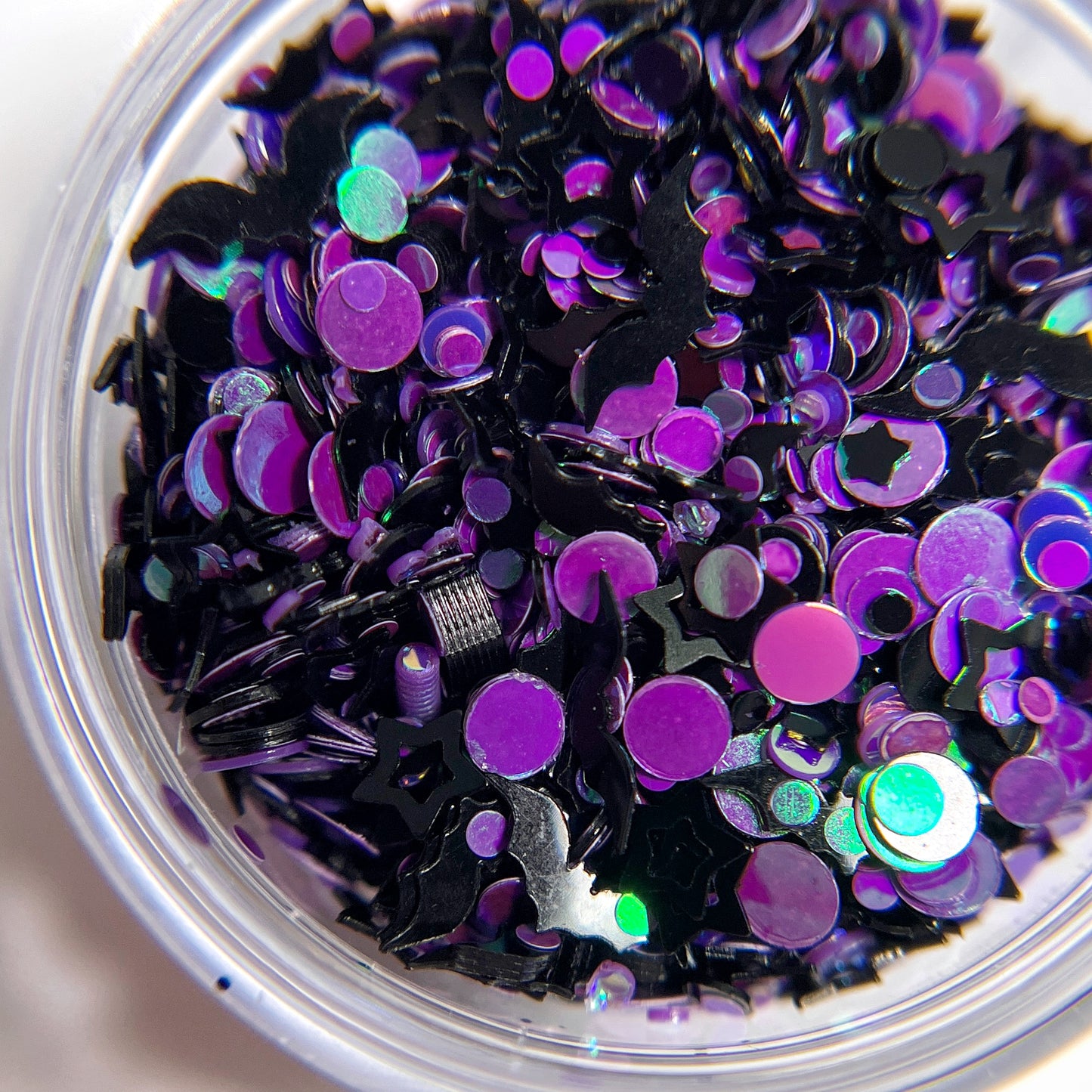 Purple and black multi-shape glitter in a clear ar on a white background. 