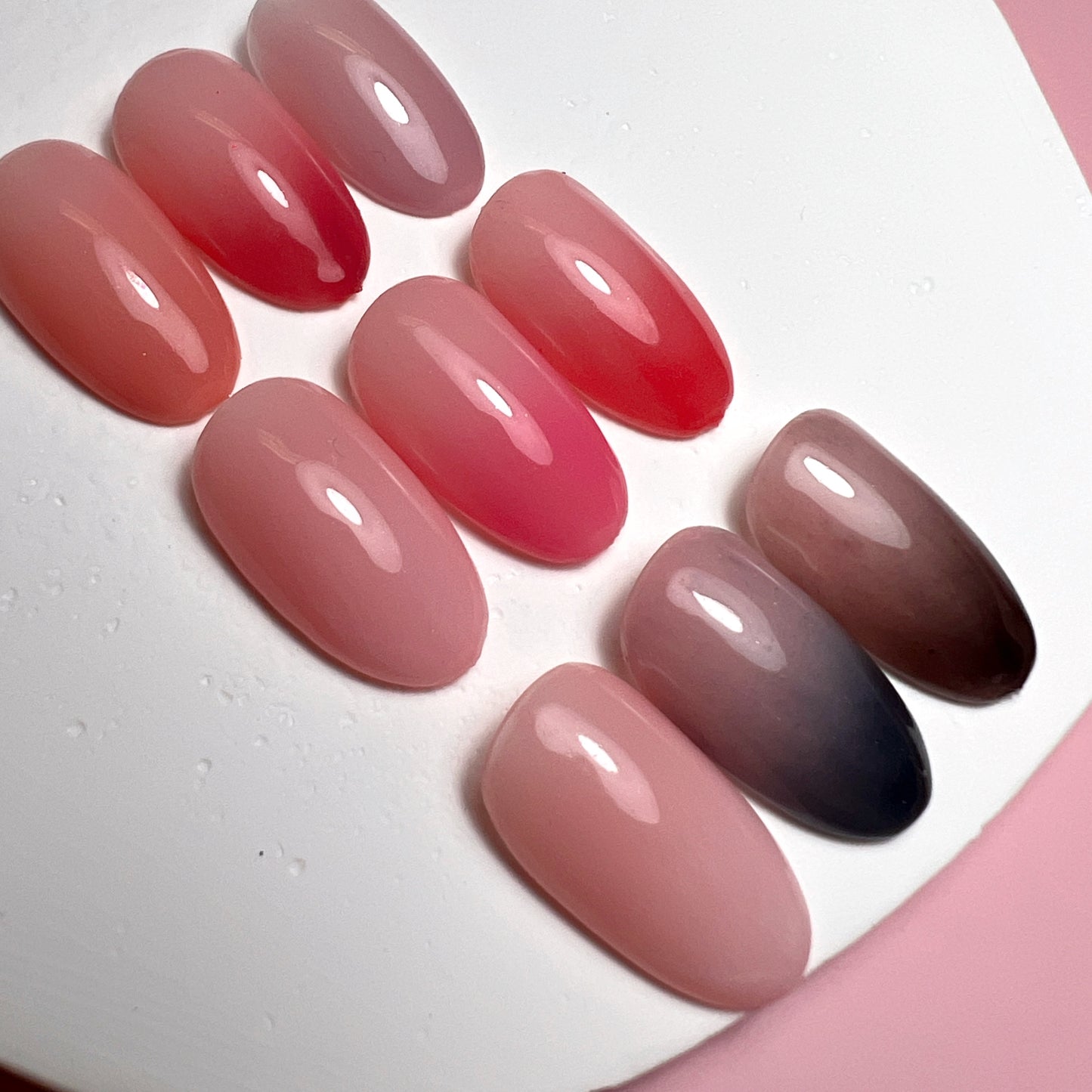 Close up photo of nail tips with gradient design on white and pink background.