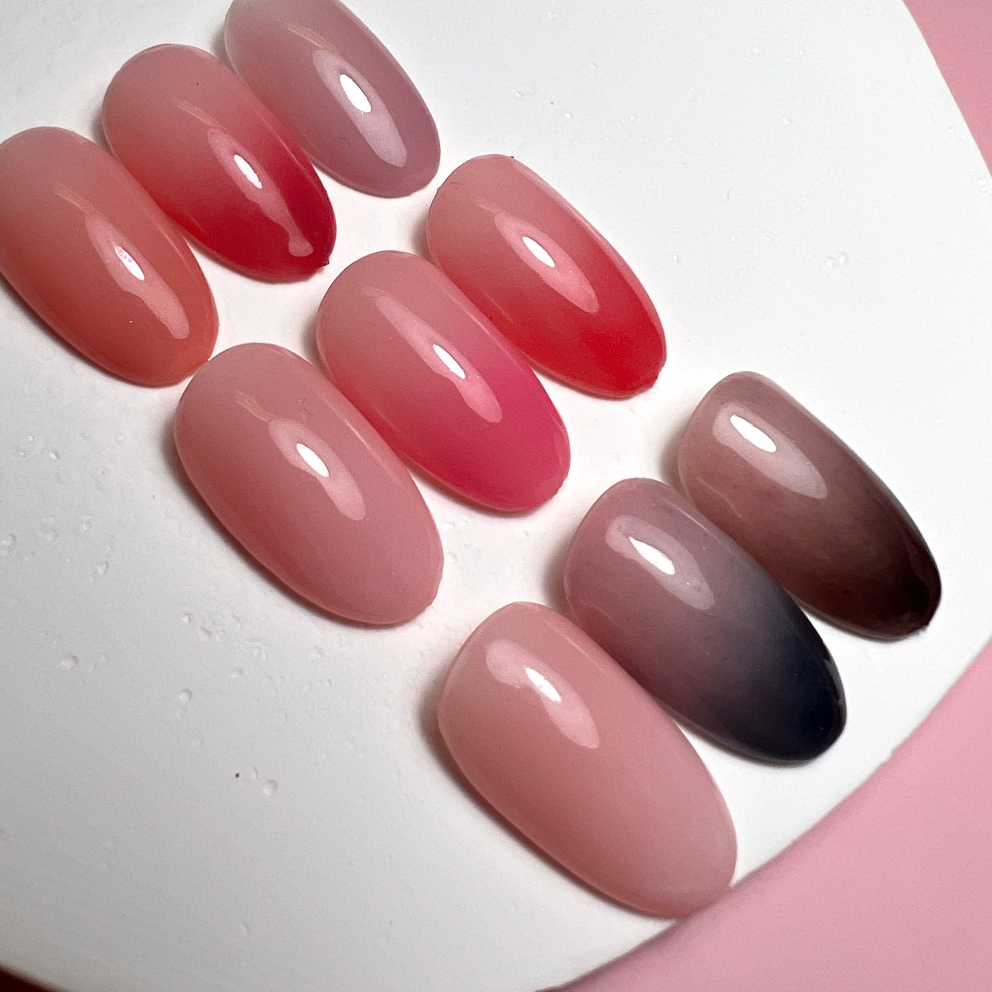 Close up photo of nail tips with gradient design on white and pink background.